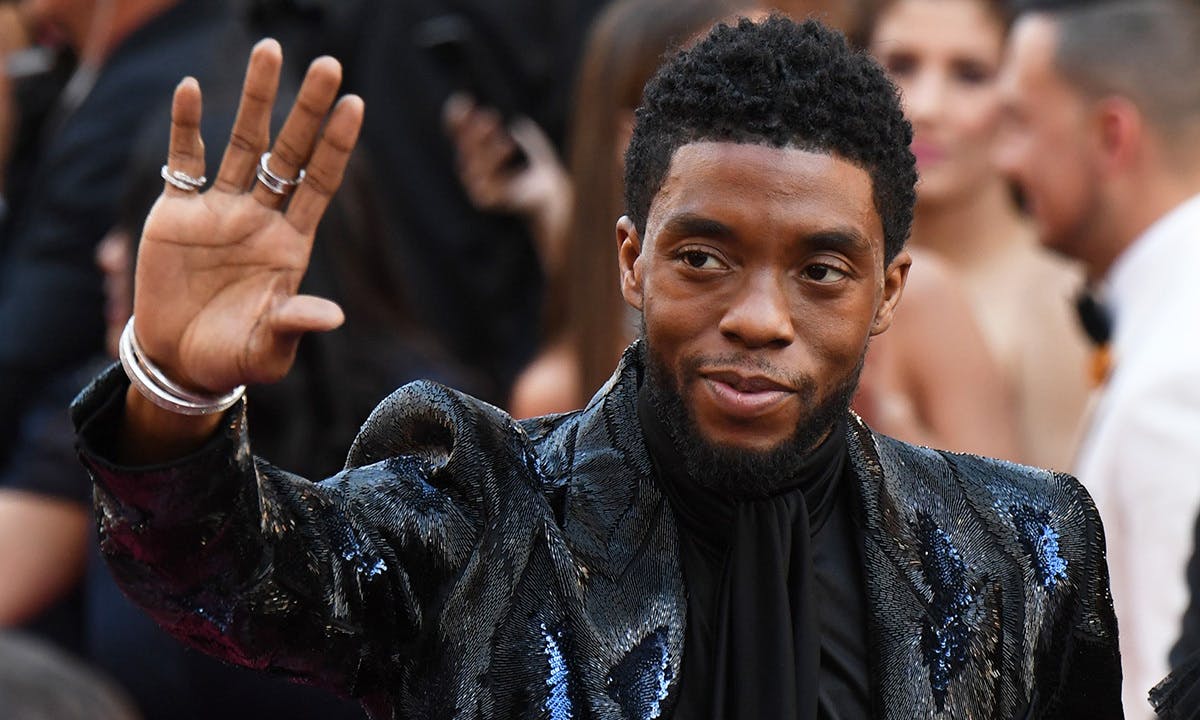 Chadwick Boseman waves at an event