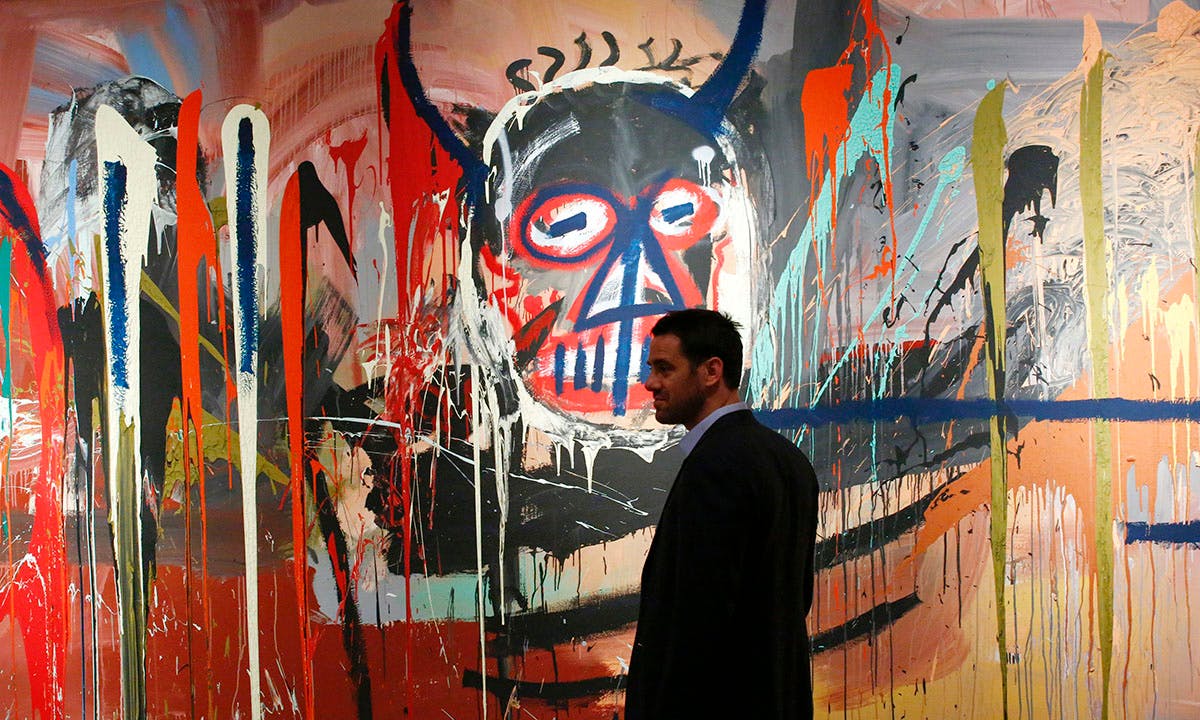 man stands next to the artwork 'Untitled' made by artist Jean-Michel Basquiat