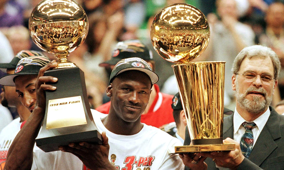 Michael Jordan (L) holds the NBA Finals Most Valuable Player trophy and former Chicago Bulls head coach Phil Jackson holds the NBA champions Larry O'Brian trophy 14 June after winning game six of the NBA Finals with the Utah Jazz at the Delta Center in Salt Lake City, UT.