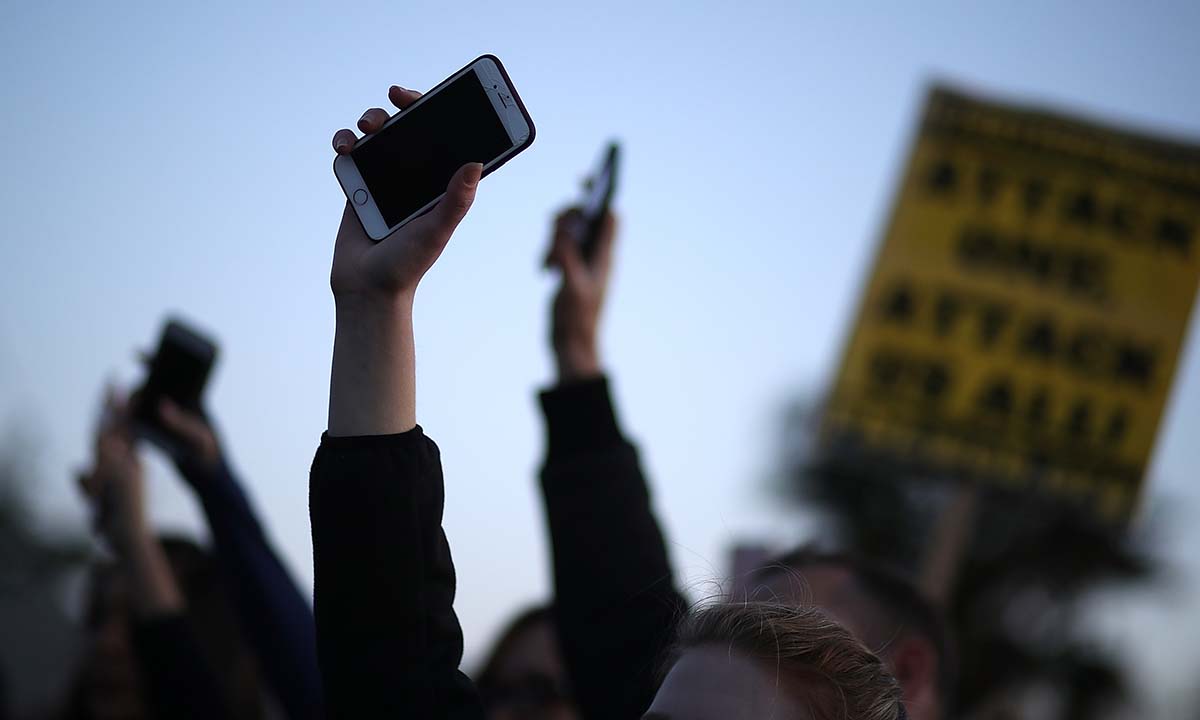 Black Lives Matter protesters hold up their cell phones during a vigil and demonstration