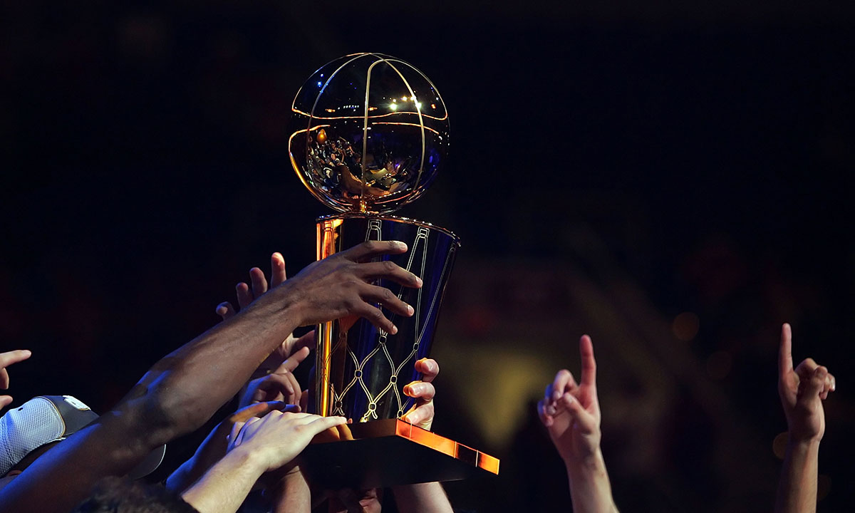 Members of the San Antonio Spurs hold up the Larry O'Brien Championship Trophy after winnin Game Four of the NBA Finals against the Cleveland Cavaliers