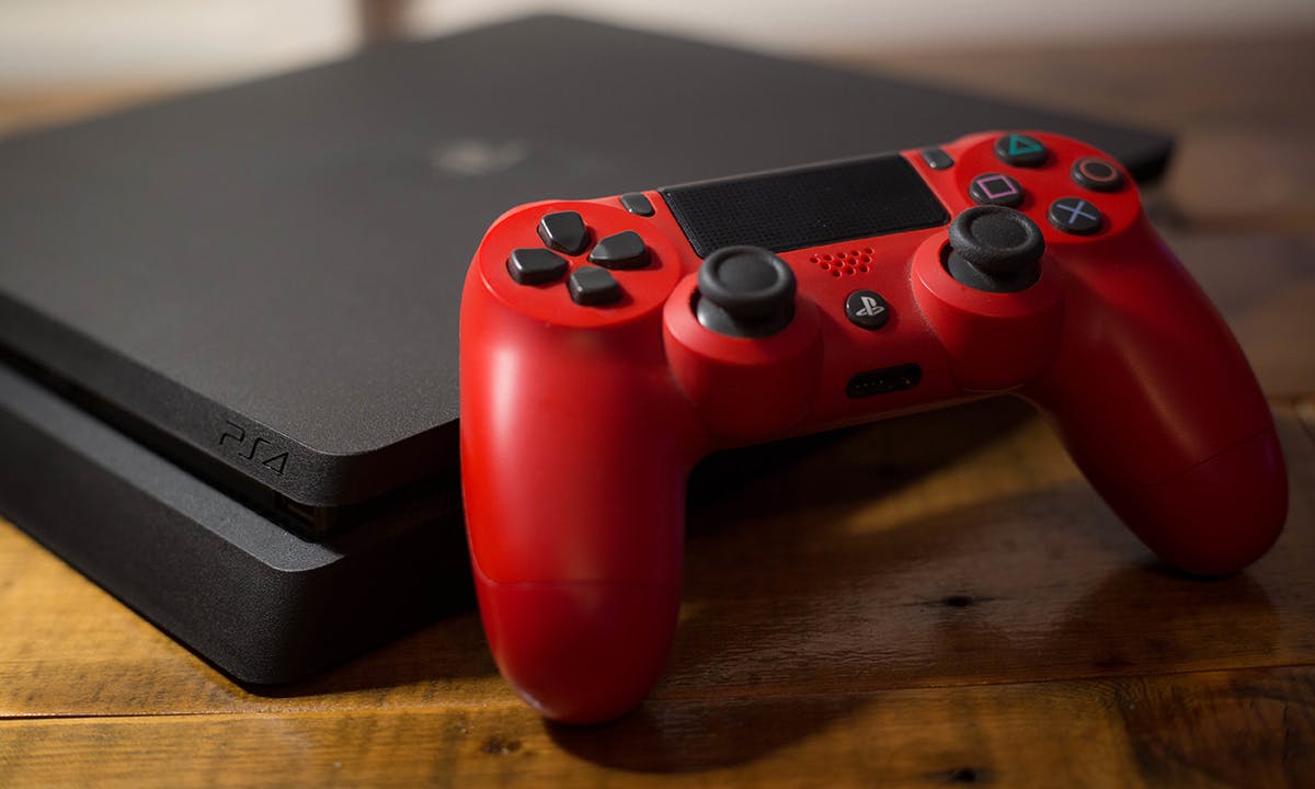 A Sony PlayStation 4 video game console with a red wireless controller