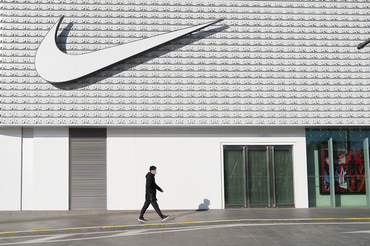 A man wearing a face mask walks past a Nike store in Central Business District, Beijing