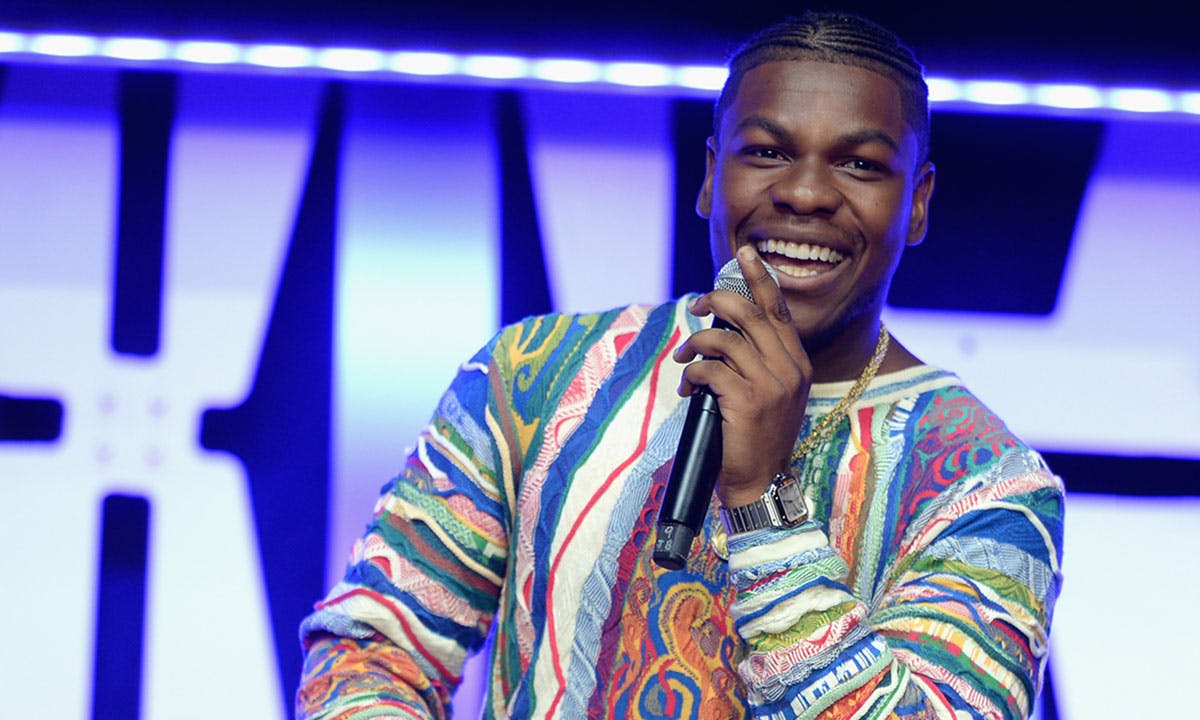 John Boyega on stage holds microphone smiling