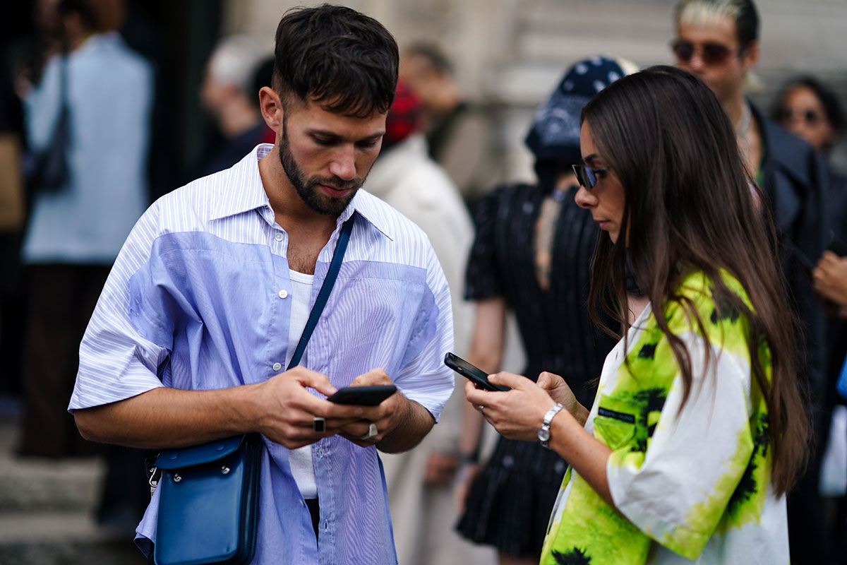 couple on their phones at Paris Fashion Week