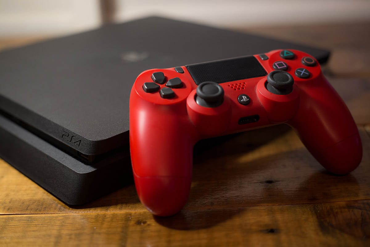 A Sony PlayStation 4 video game console with a red wireless controller