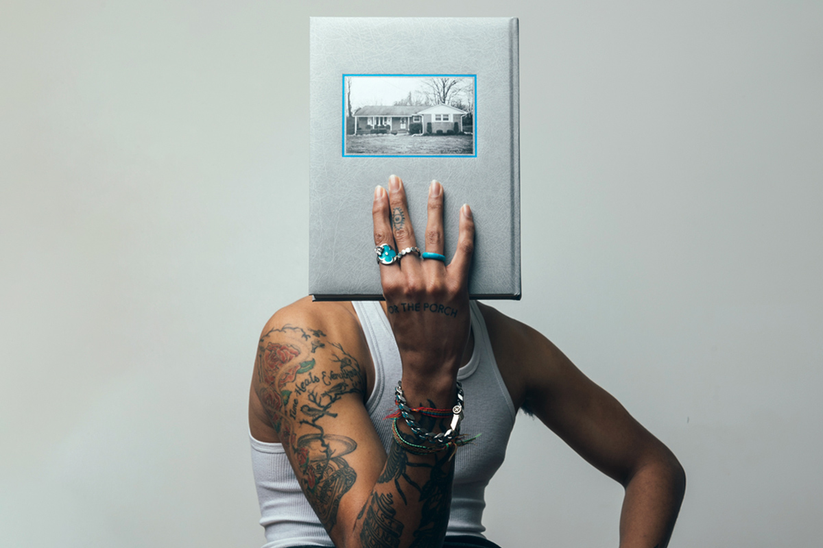 Cam Hicks covers face with For the Porch book