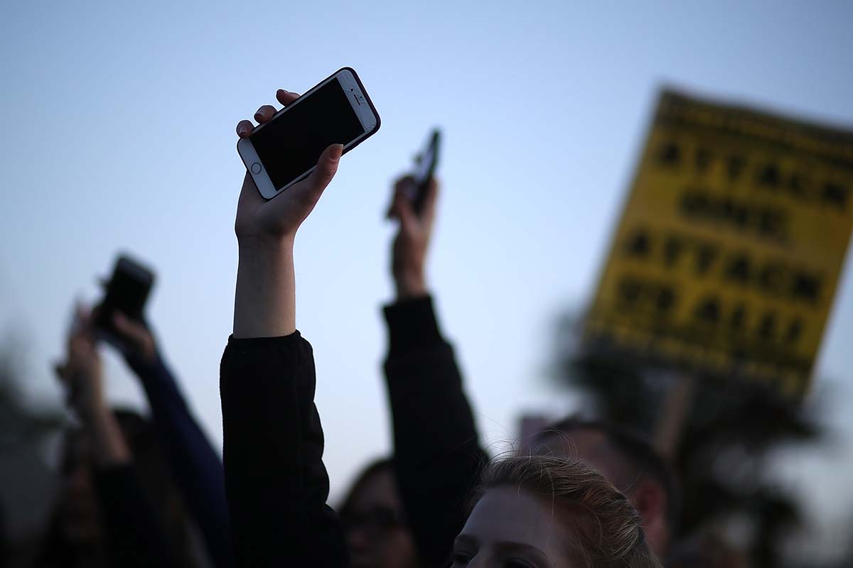 Black Lives Matter protesters hold up their cell phones during a vigil and demonstration