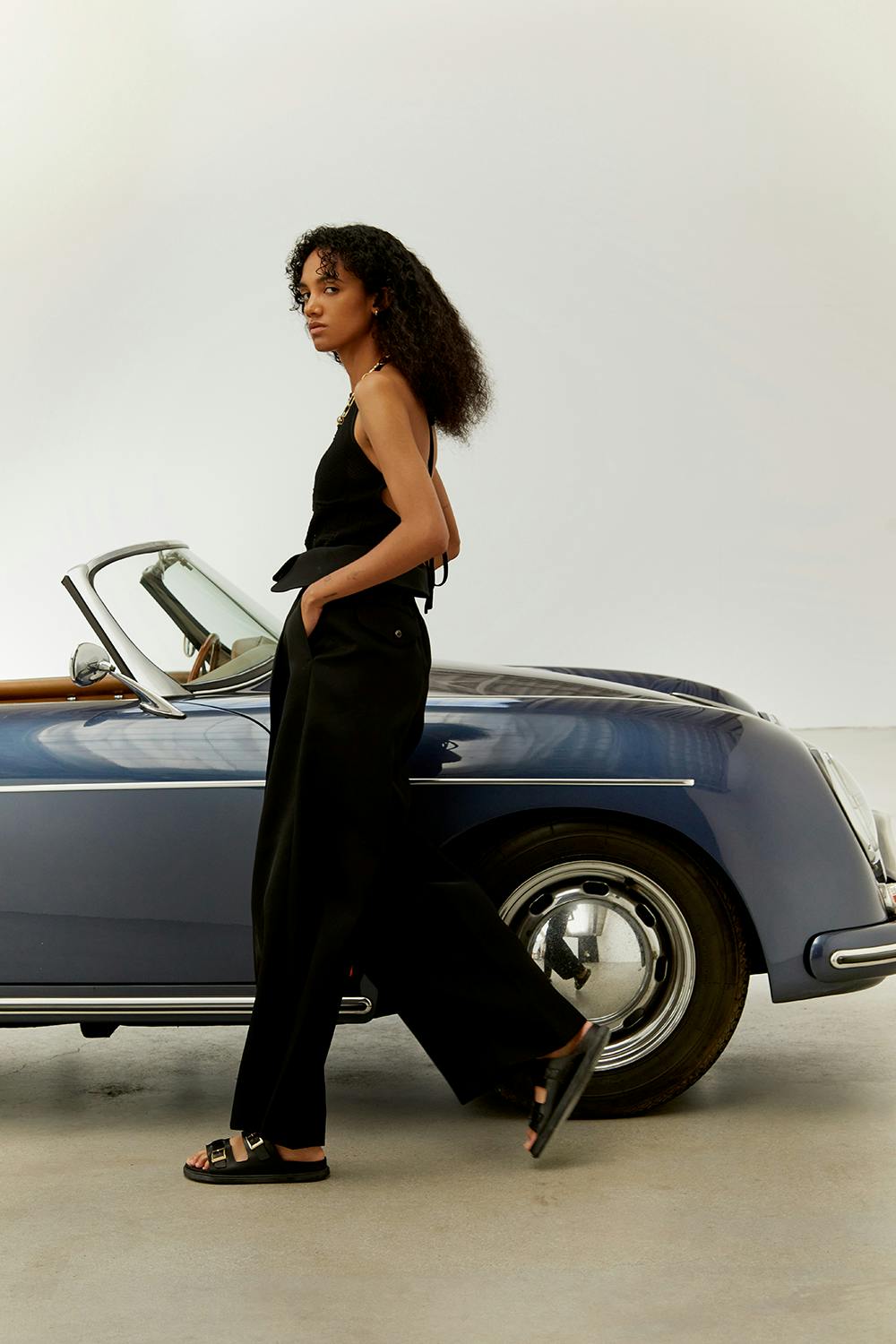 A model wears Birkenstock's St. Barths sandal while walking next to a vintage car