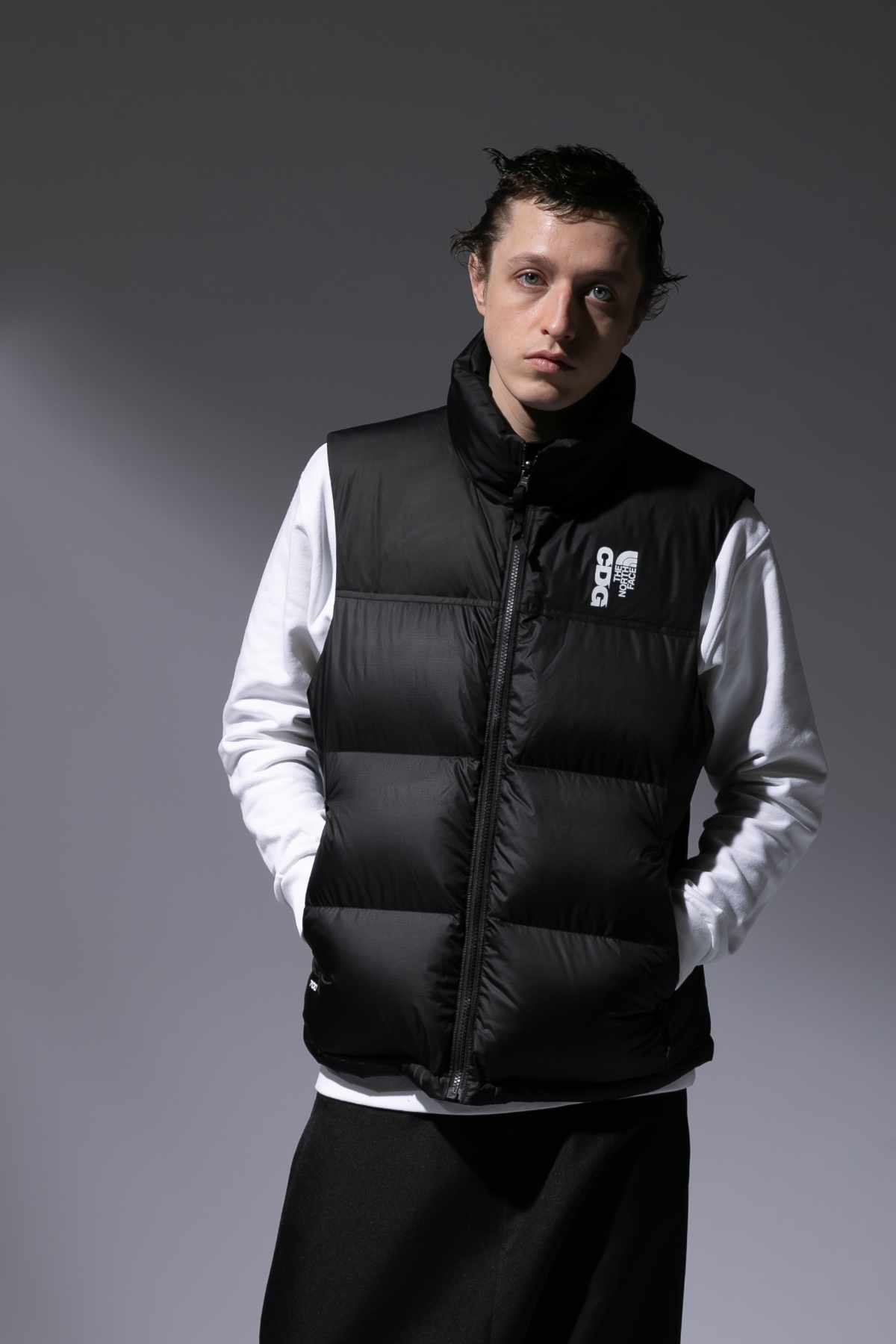 A model wears the CDG x The North Face collaboration, with a puffer vest