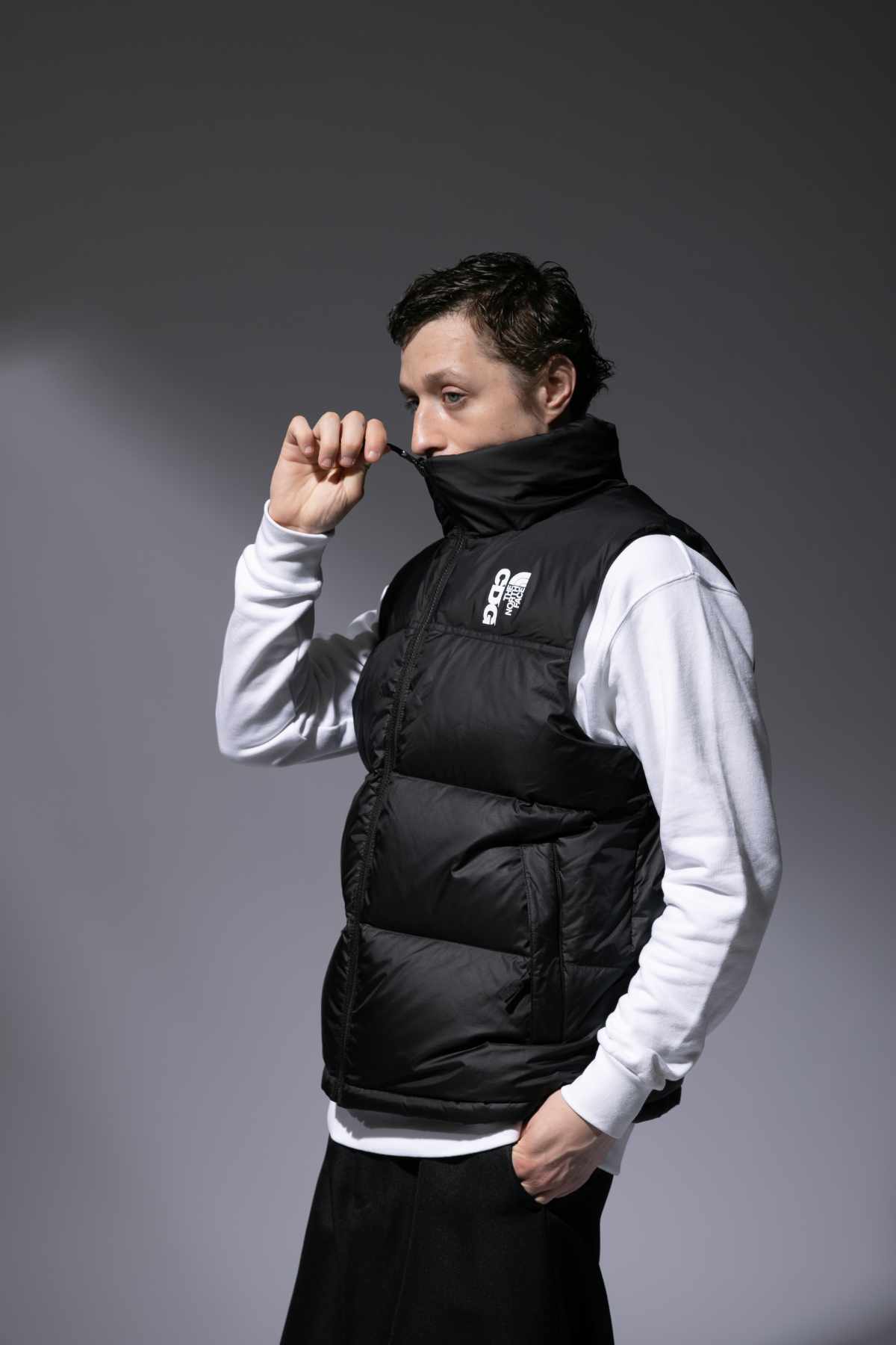 A male model wears the CDG x The North Face collaborative puffer vest