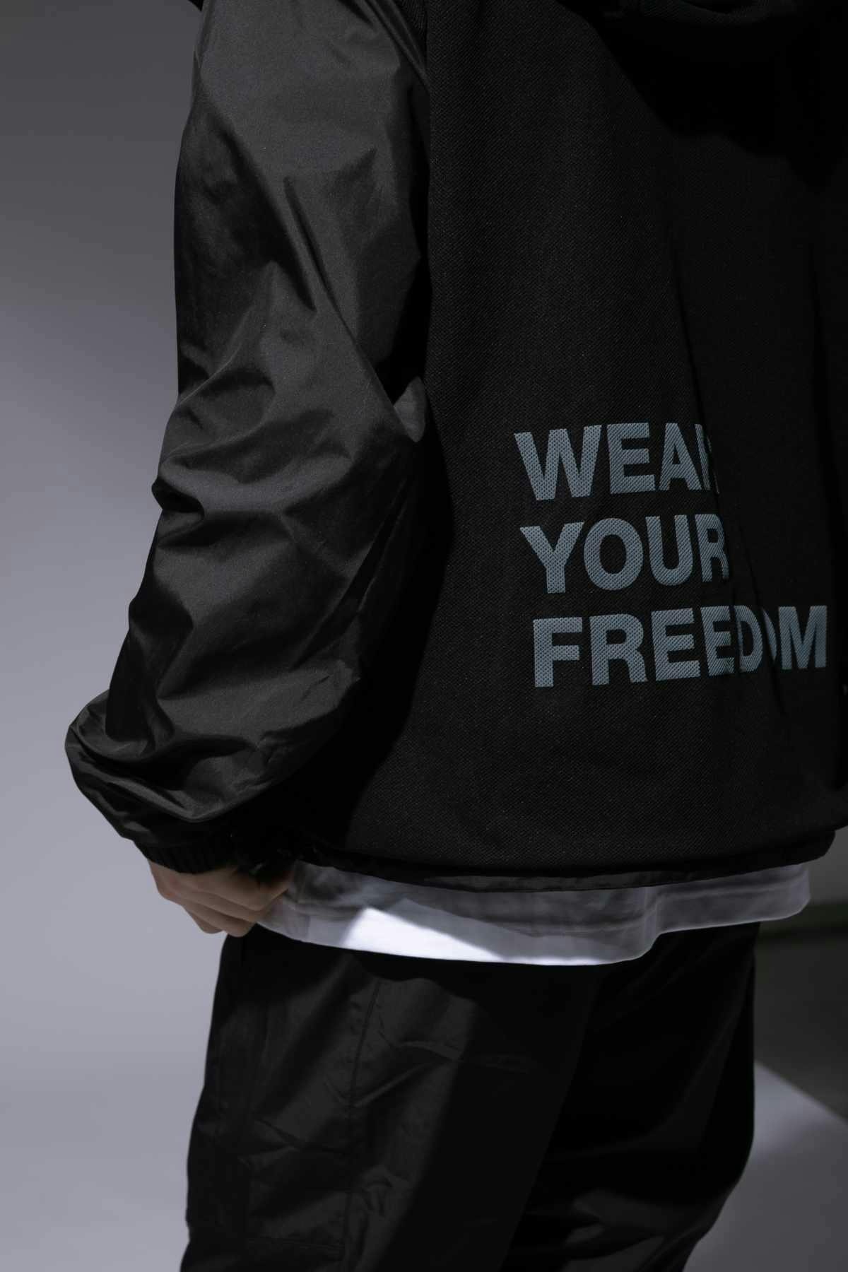 A male model wears the CDG x The North Face collaborative hooded zip-up jacket with "WEAR YOUR FREEDOM" text