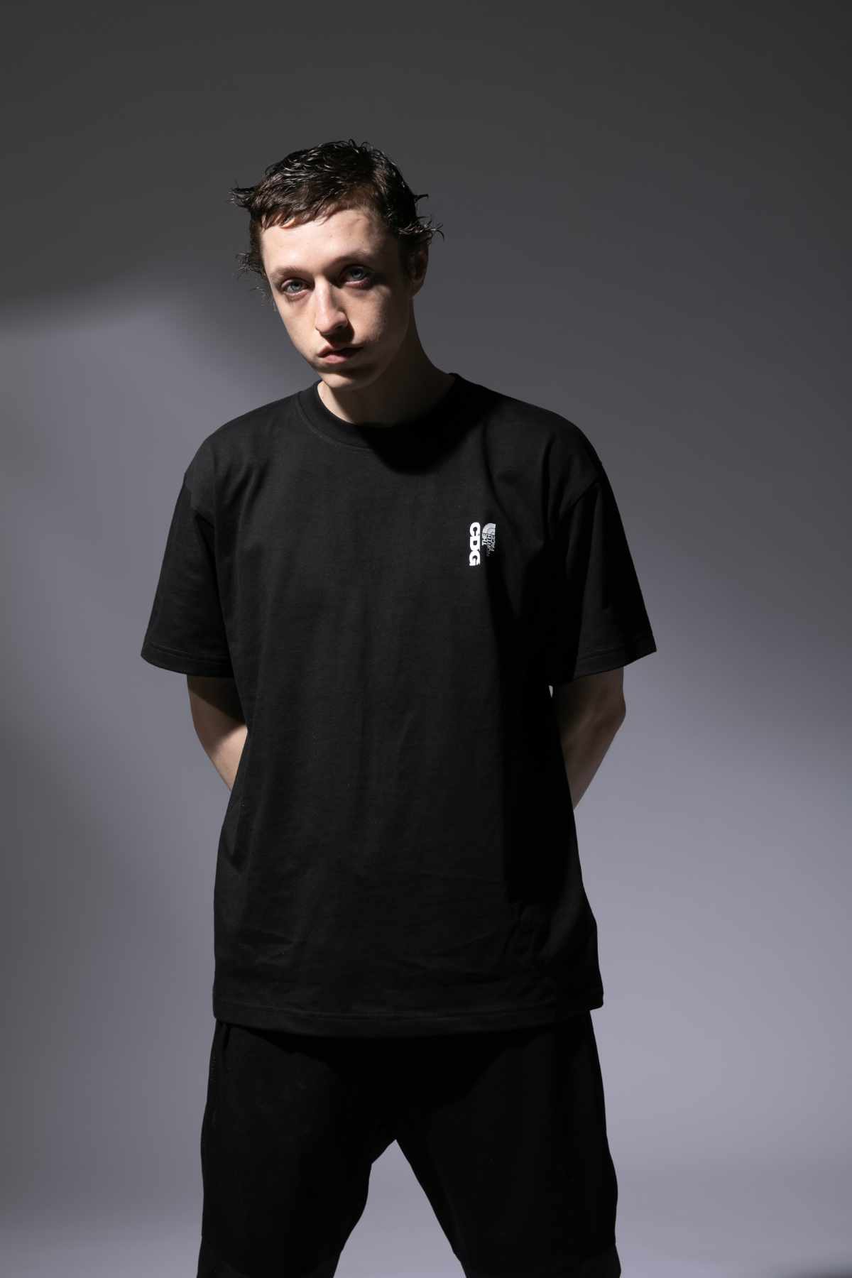 A male model wears the CDG x The North Face collaborative black T-shirt and matching trousers