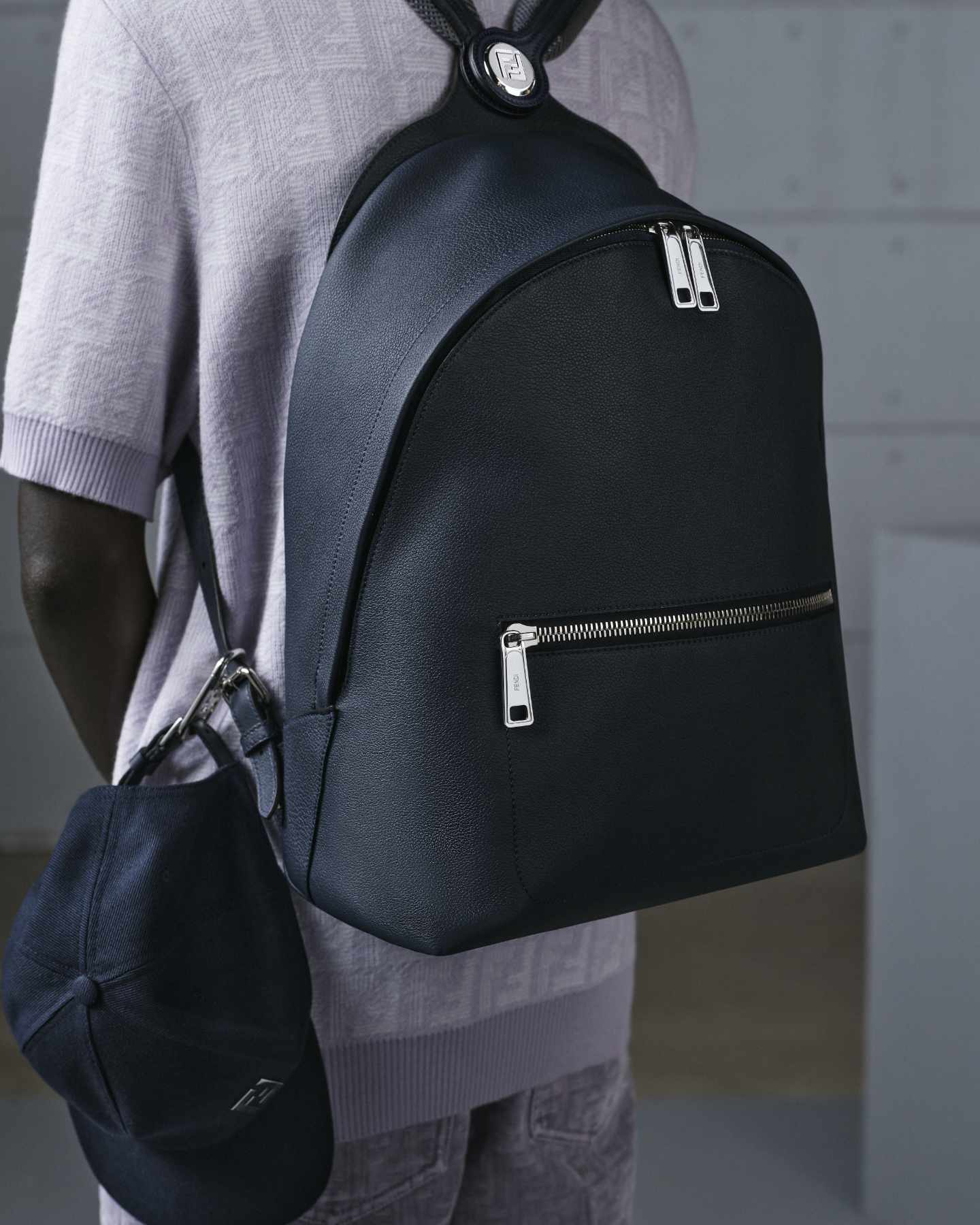 A model wears Fendi's Chiodo Backpack in navy grain leather