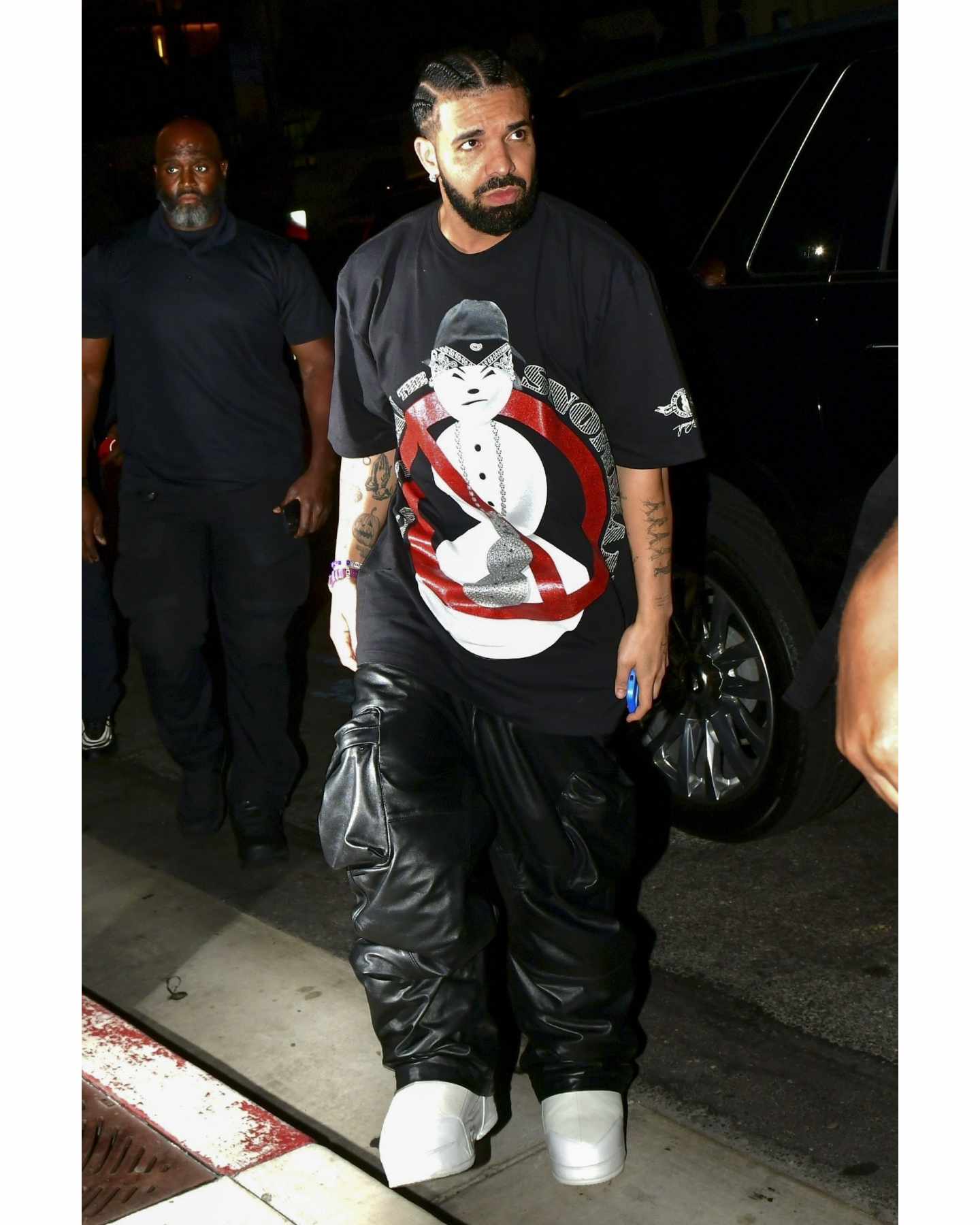 Drake wears snowman T-shirt, leather cargo pants & white platform shoes at night