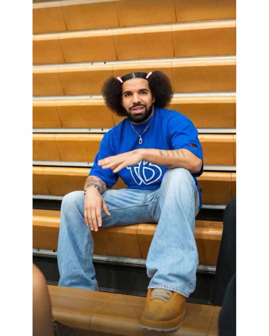 Drake wears pink hairclips, a blue Fubu T-shirt, baggy jeans & oversized sneakers