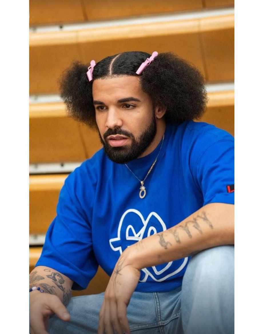 Drake wears a blue Fubu T-shirt & pink hairclips in his hair