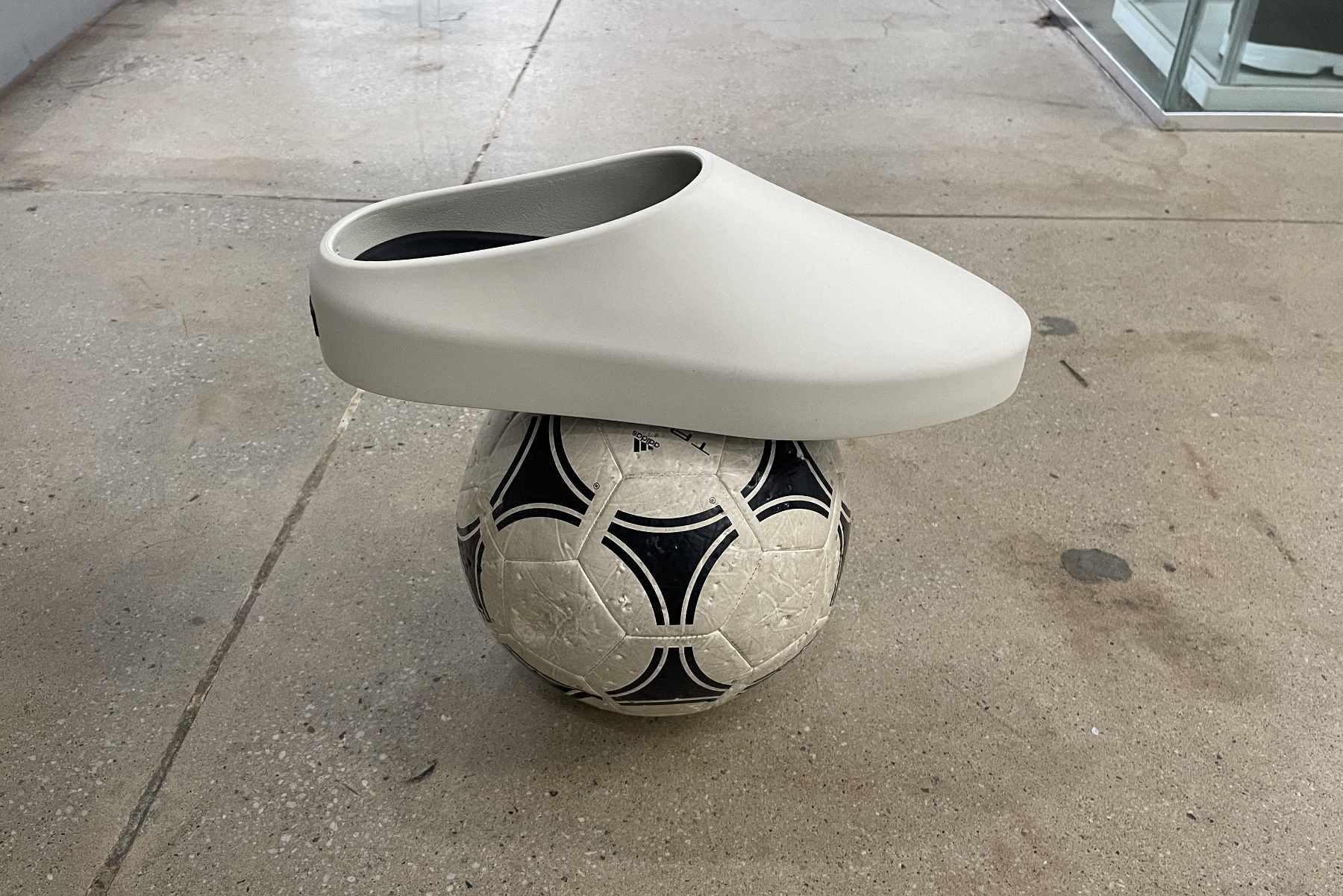 Fear of God's California 2.0 slip-on shoe in cream balancing on a soccerball