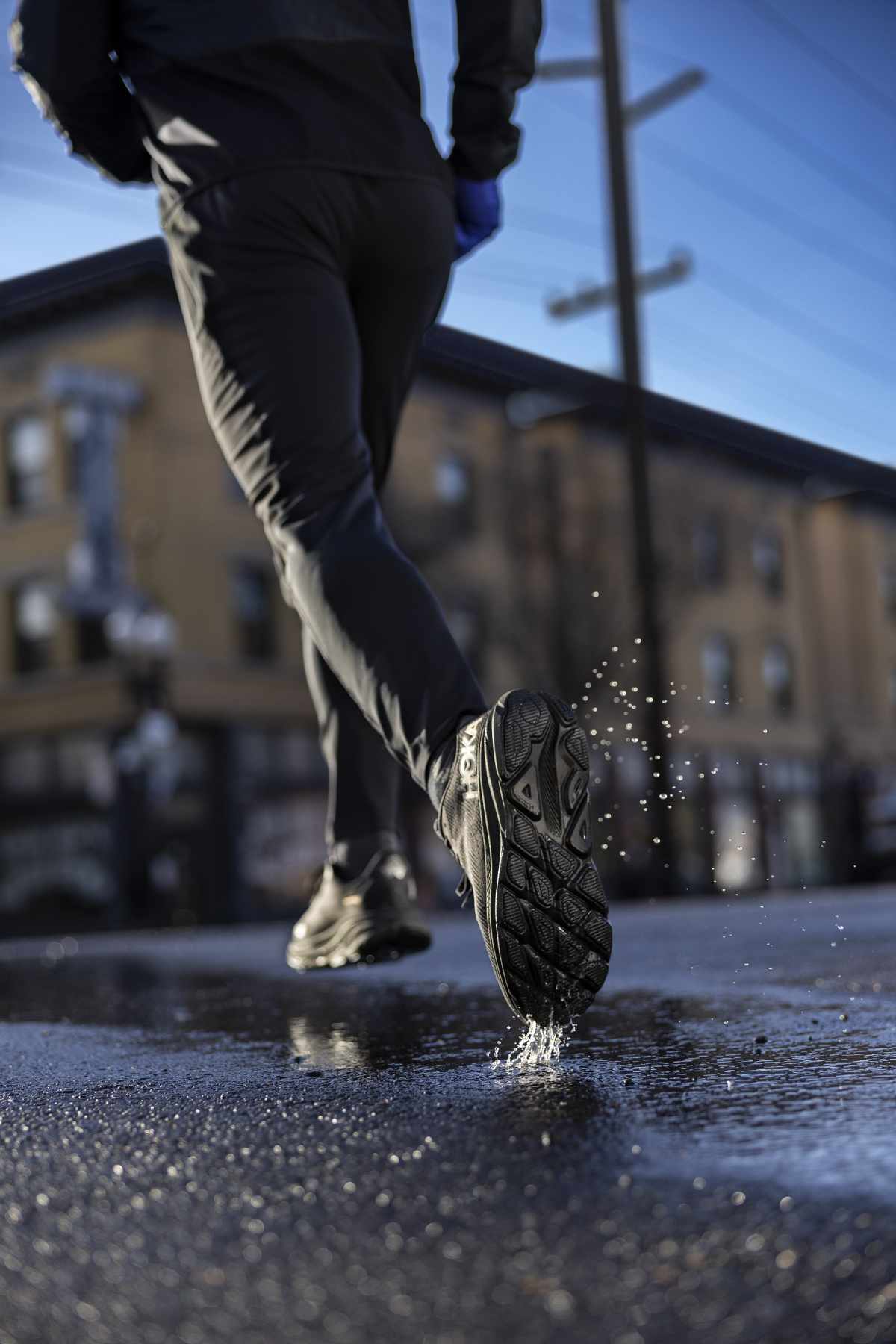 A running person wearing HOKA's Clifton 9 sneaker in a black GORE-TEX-lined colorway