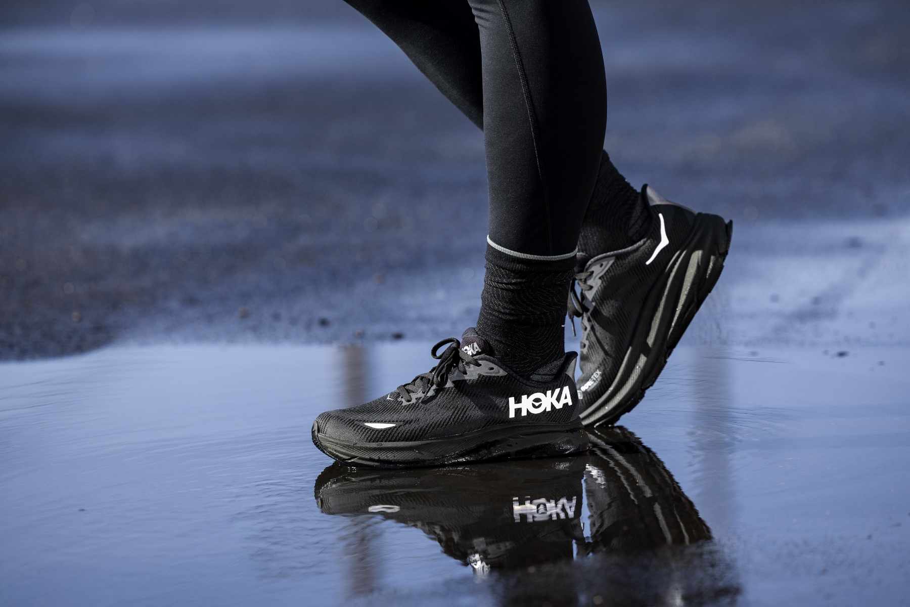 A runner wears HOKA's Clifton 9 sneaker in a black GORE-TEX-lined colorway