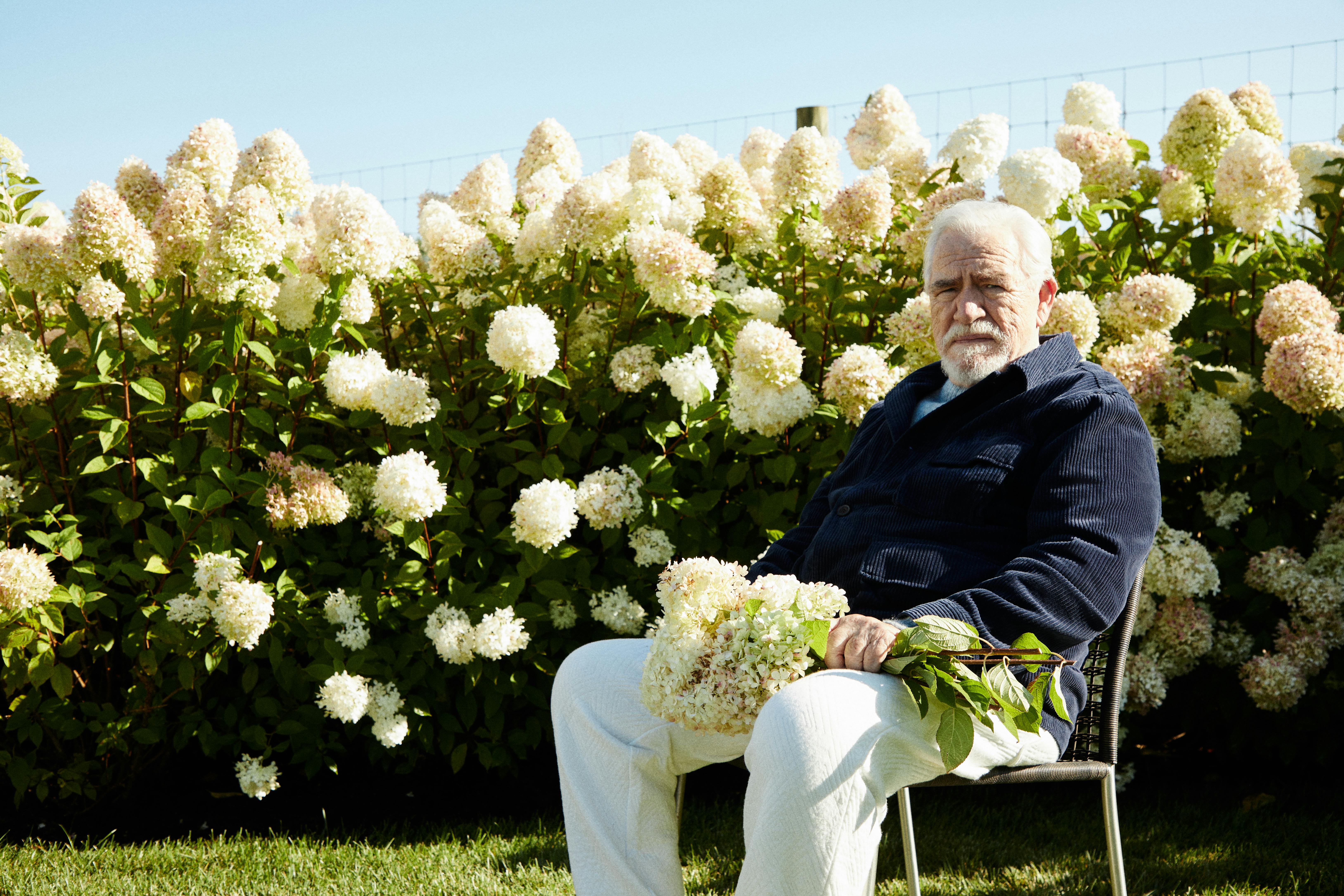 A photograph of Brian Cox, the actor famous for portraying Logan Roy on 'Succession,' wears a KITH shirt in front of a field of flowers