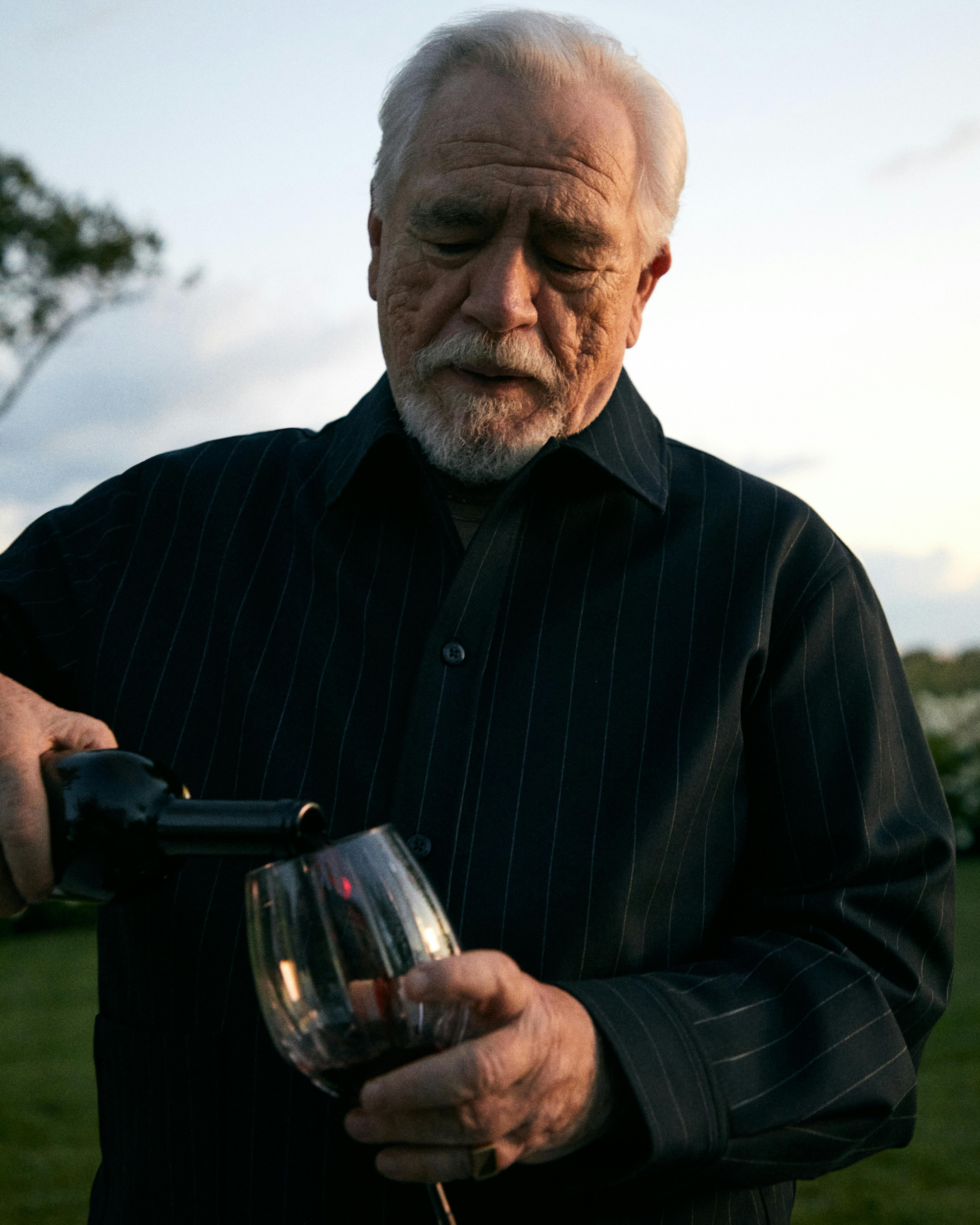 A photograph of Brian Cox, the actor famous for portraying Logan Roy on 'Succession,' wears a black Kith shirt, pouring wine