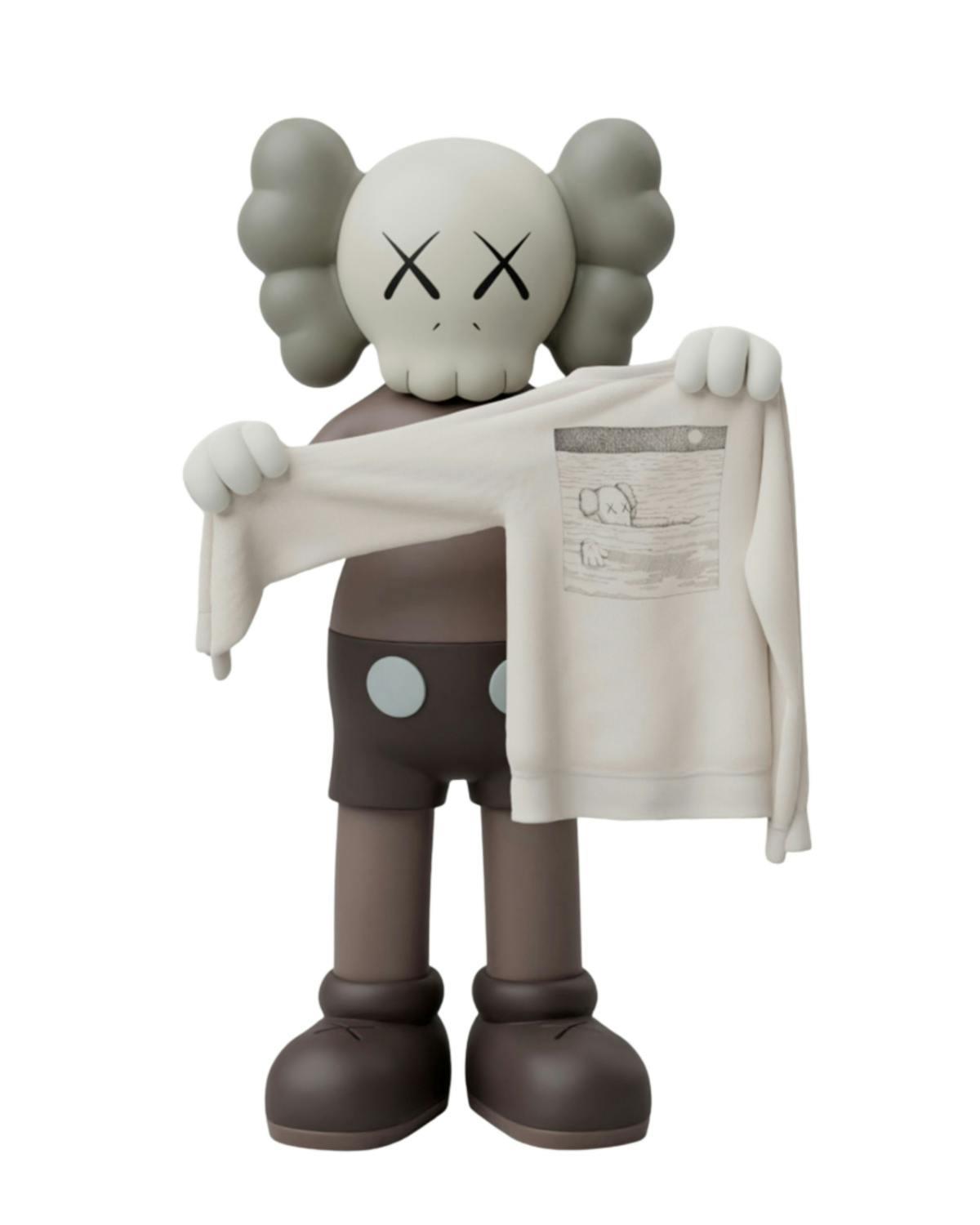 A KAWS Companion holds a UNIQLO x KAWS T-shirt and book