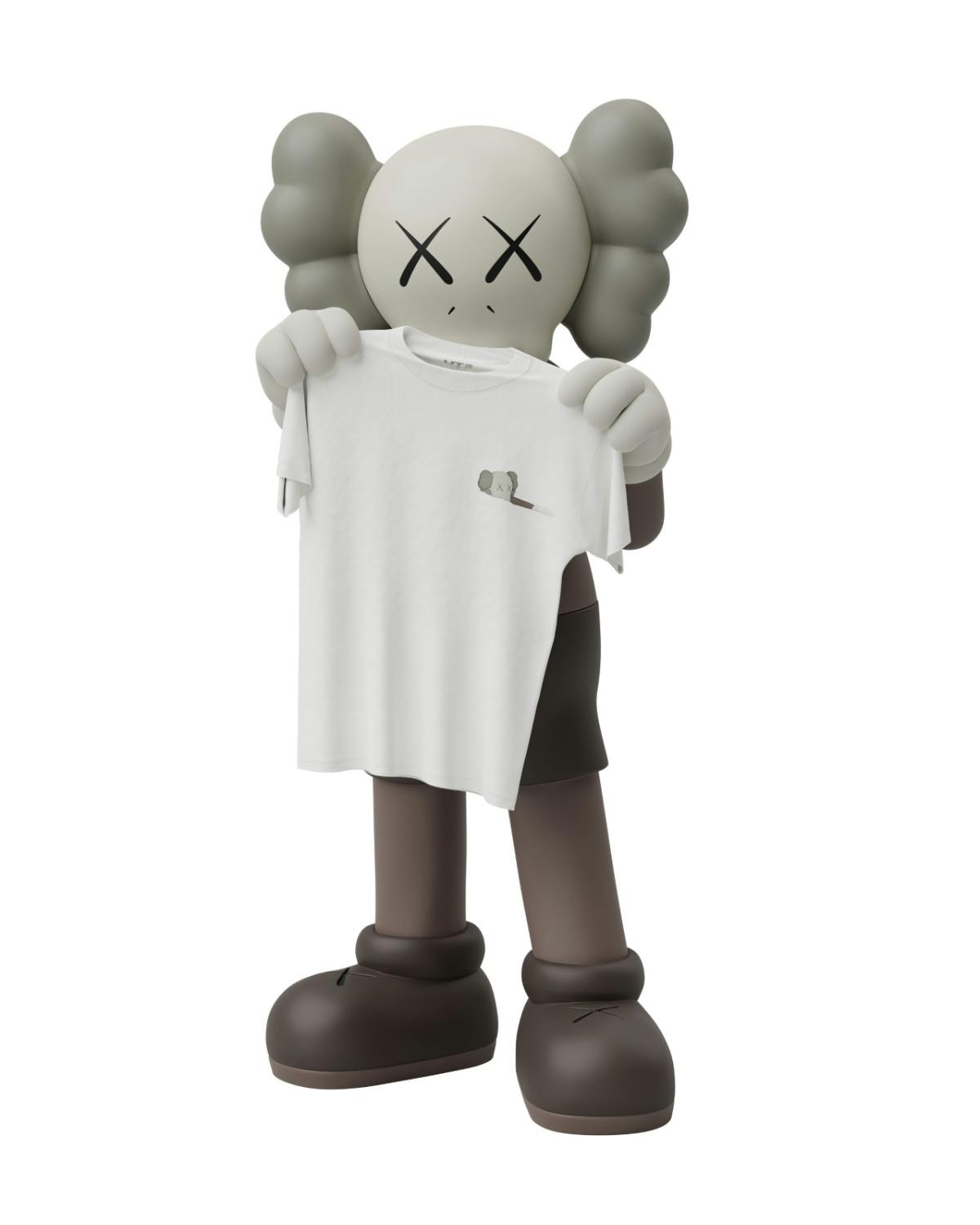 A KAWS Companion holds a UNIQLO x KAWS T-shirt and book