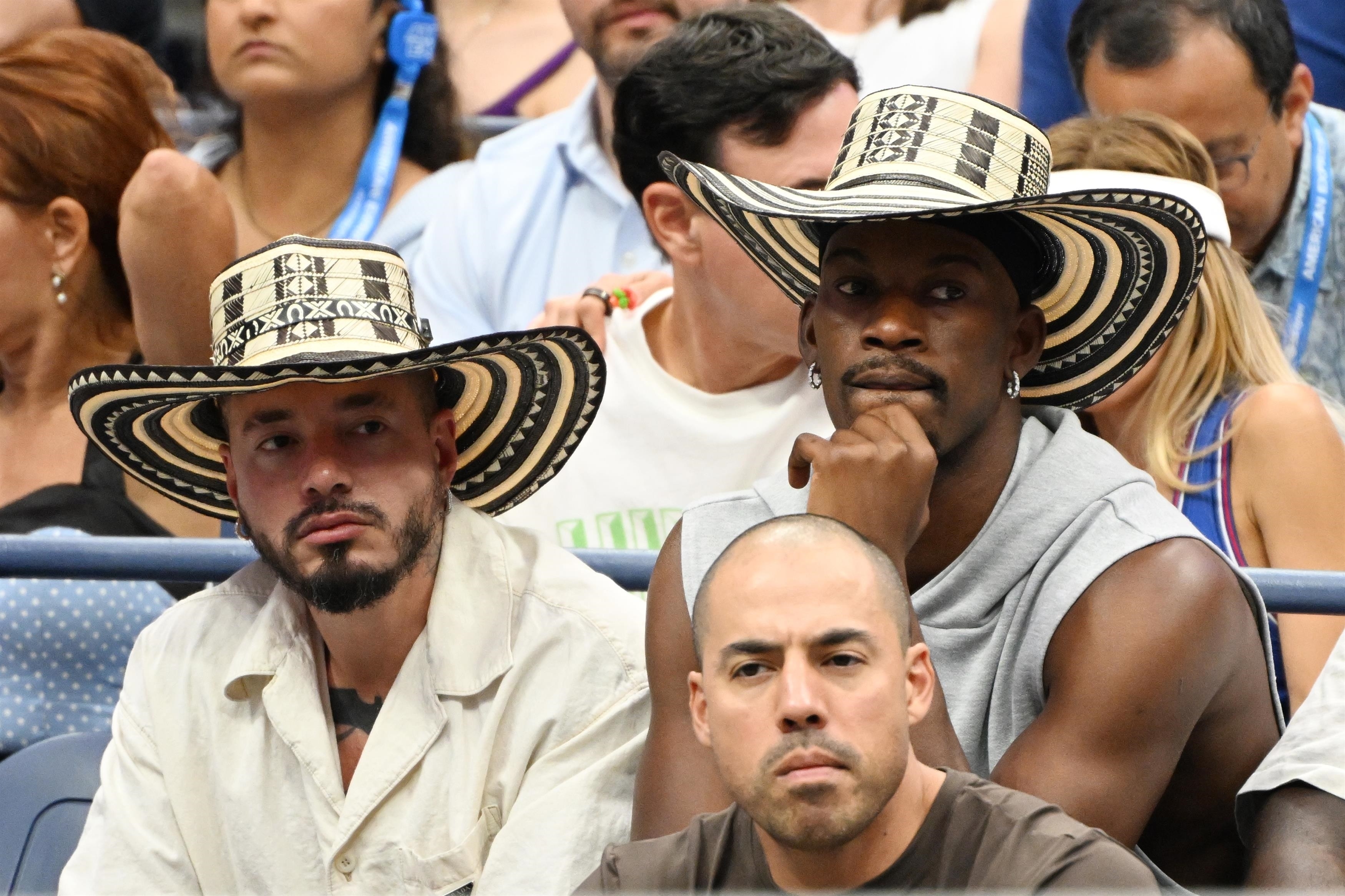 Jimmy Butler & J Balvin sit next to each other at the 2023 US Open wearing matching hats