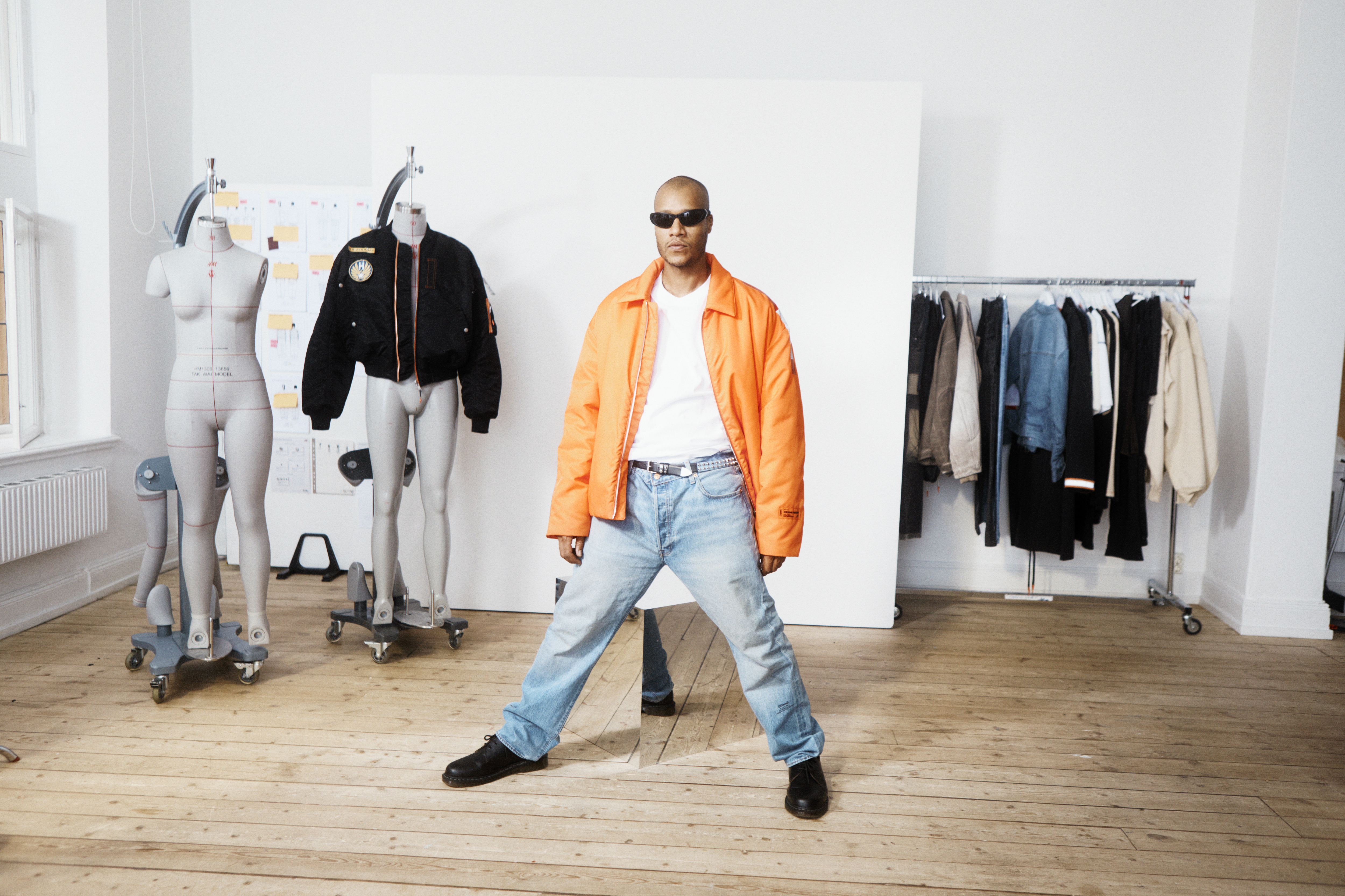 Heron Preston & H&M's menswear directors reveal the H2 collaboration, sitting in a room with mannequins and clothes on racks