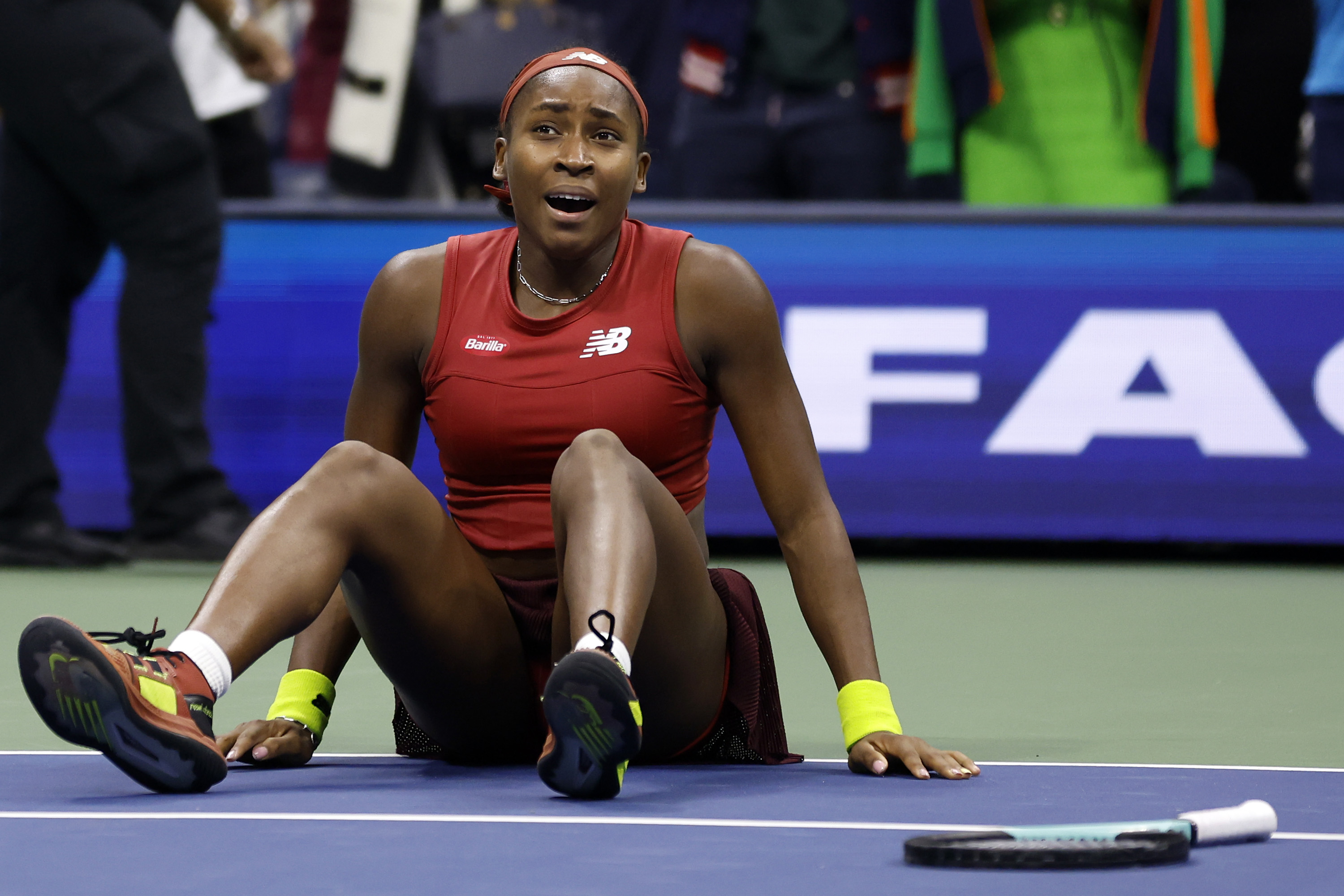 Coco Gauff, wearing a red Barilla & New Balance top, celebrates her victory at the 2023 US Open