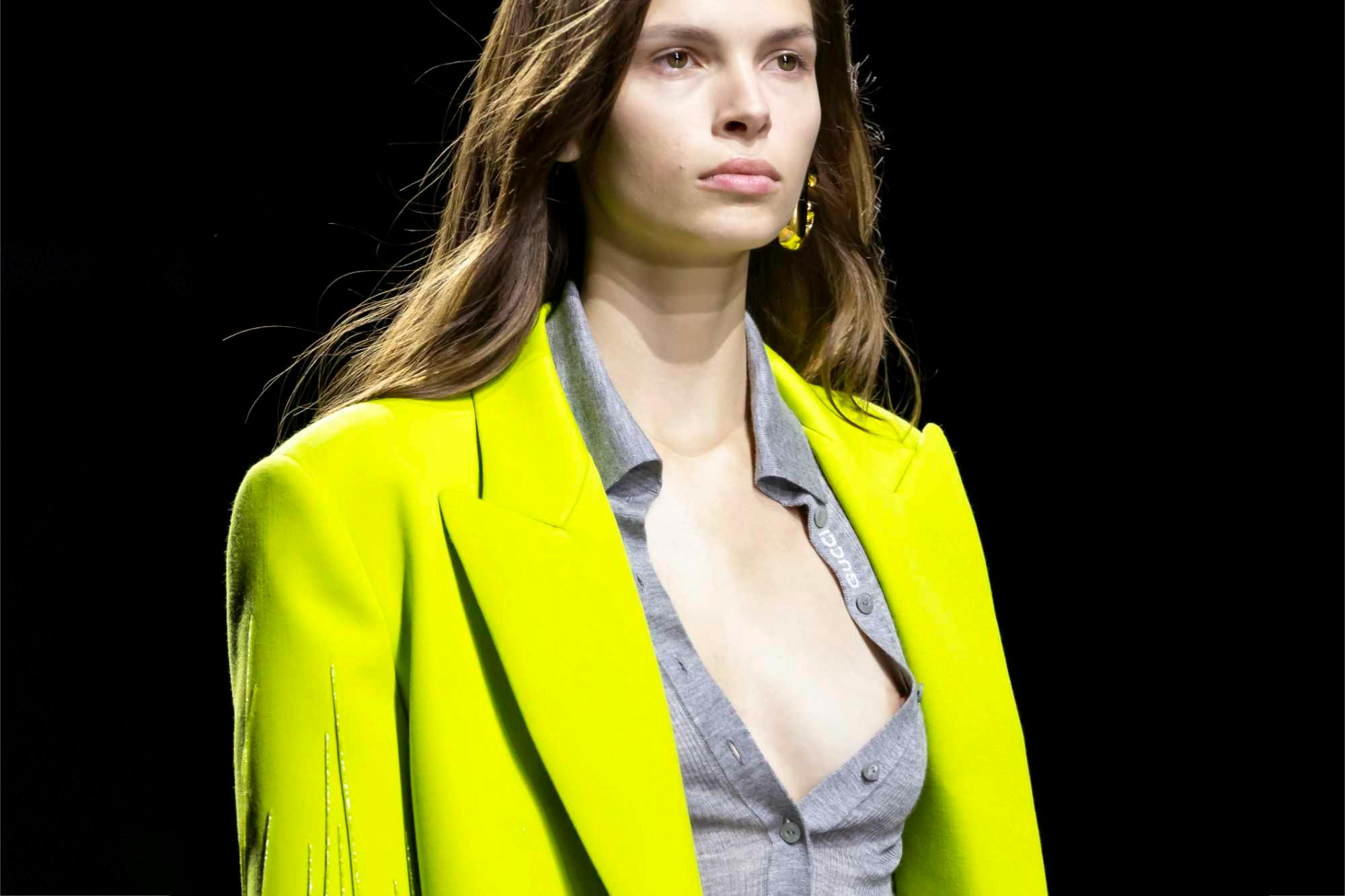 A model wears a yellow coat and unbuttoned cardigan from Gucci's Spring/Summer 2024 collection