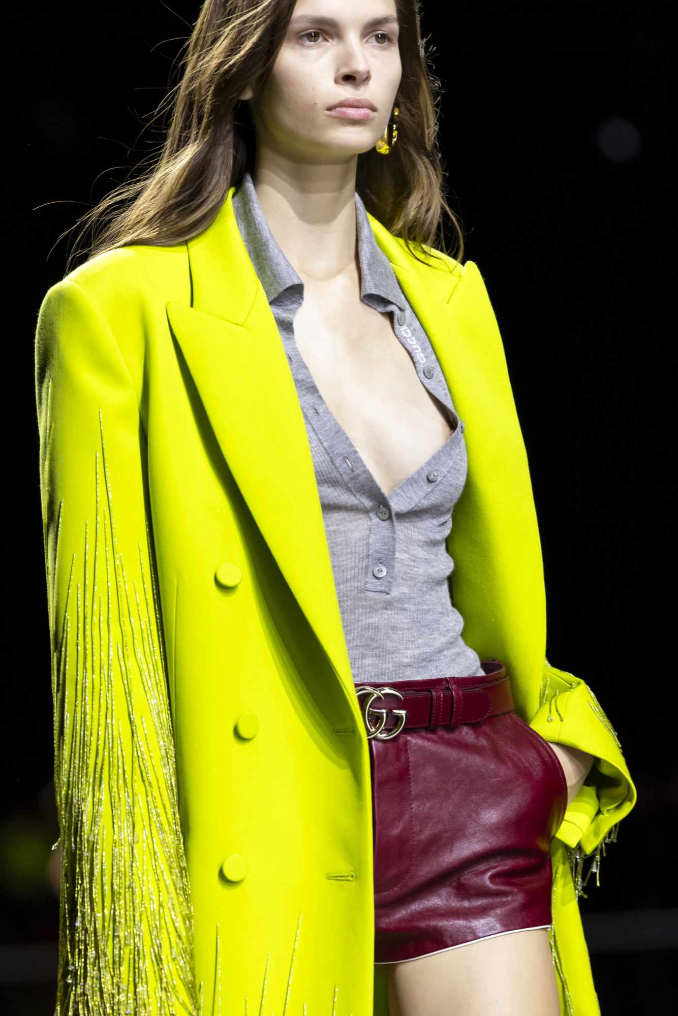 A model wears a yellow coat and unbuttoned cardigan from Gucci's Spring/Summer 2024 collection