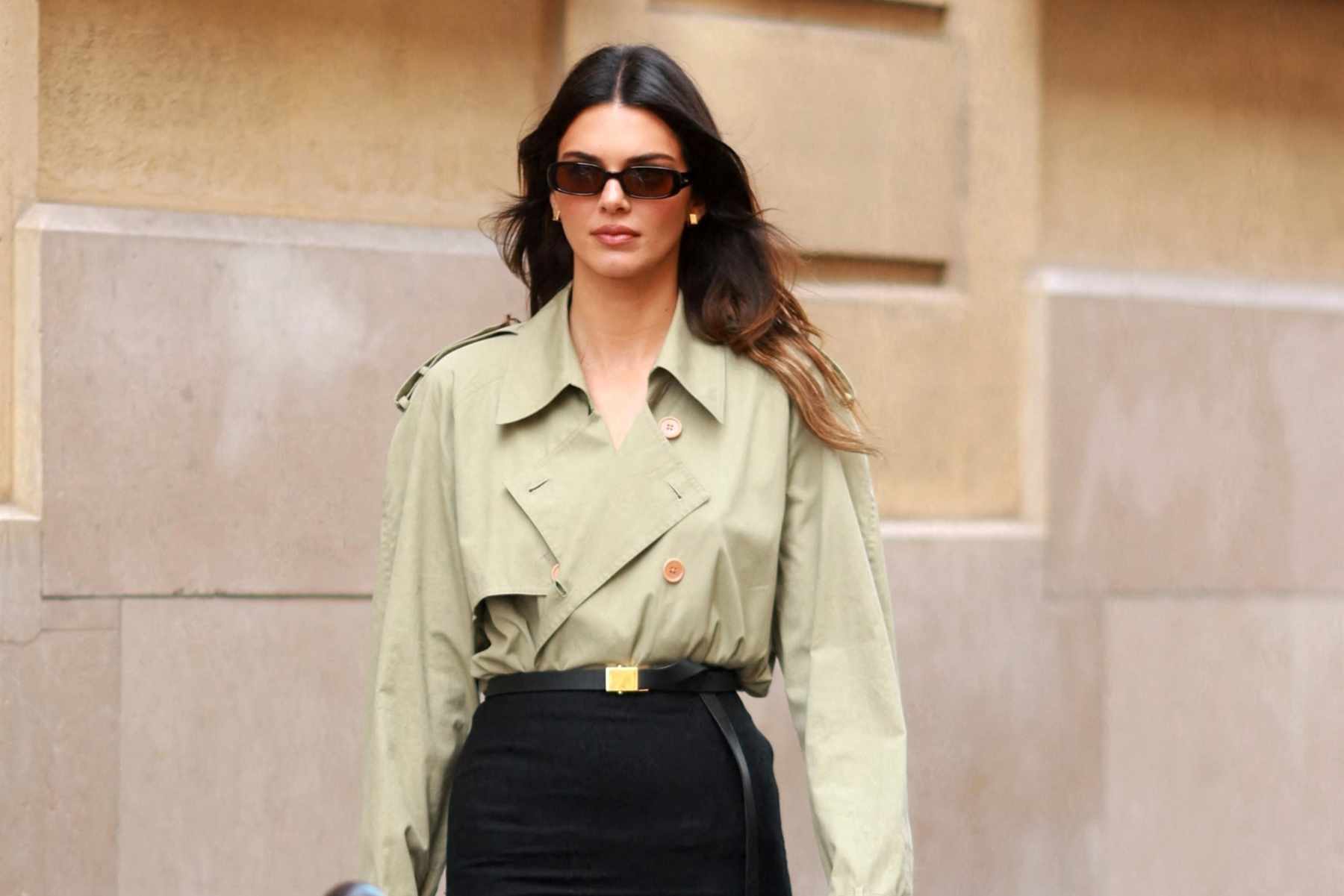 Kendall Jenner wears a trench coat tucked into a pencil skirt with black loafers and leather handbag outside of The Row's Spring/Summer 2024 runway collection