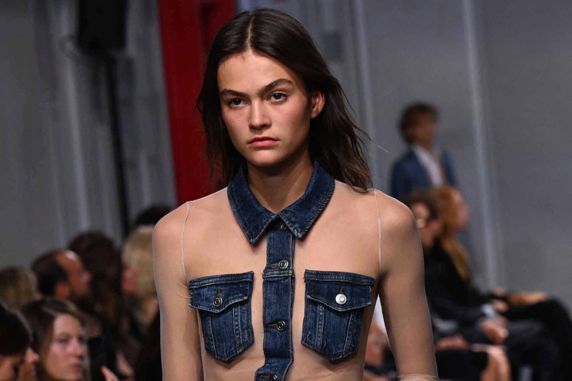 A model wears a see-through shirt with denim patches from Coperni's Spring/Summer 2024 collection runway