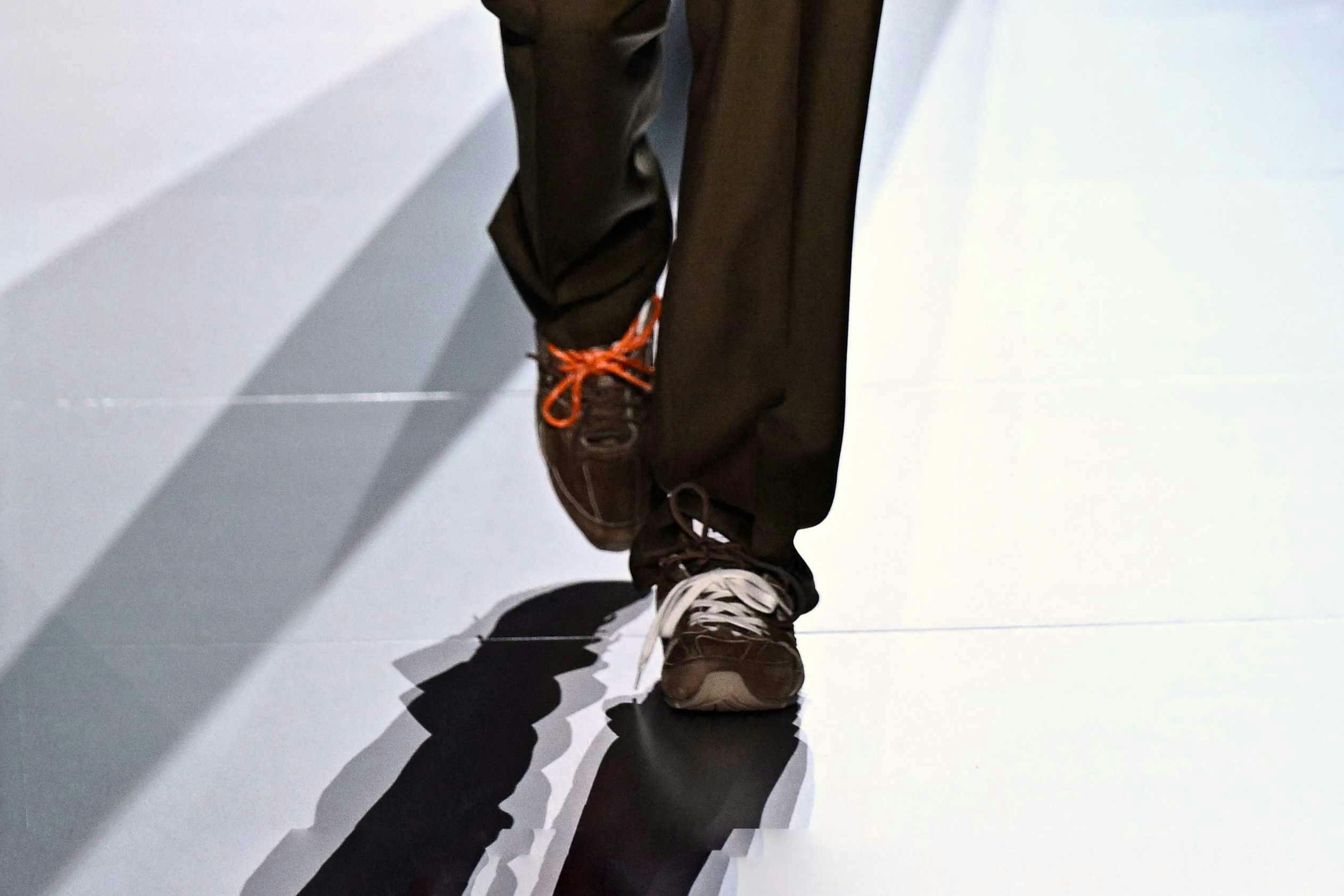 A model wears a brown Miu Miu top, matching slacks, and the latest Miu Miu x New Balance 530 sneaker collab on the SS24 runway in Paris