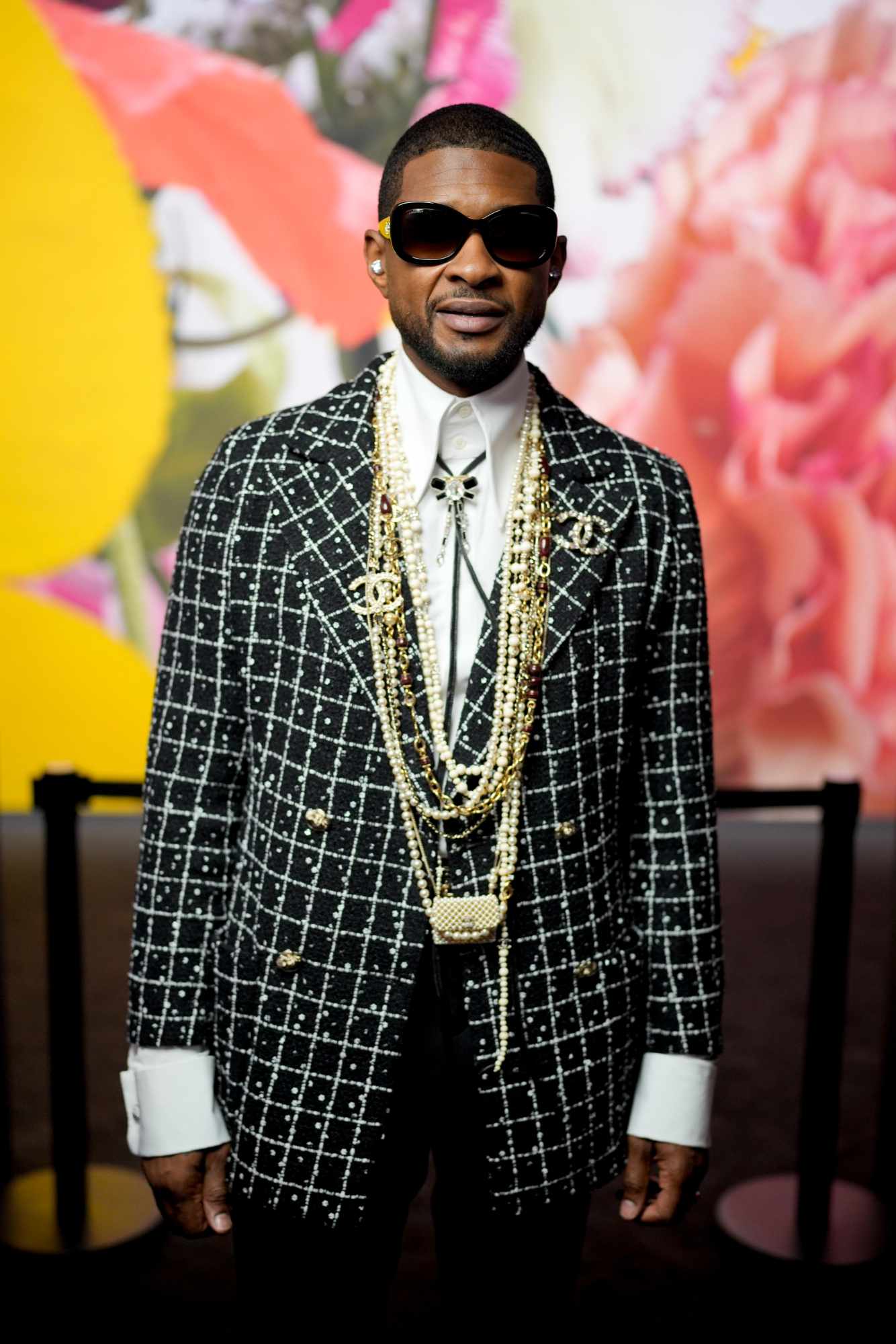 Usher wears sunglasses & grey tweed Chanel outfit with pearls at Paris Fashion Week on October 3, 2023