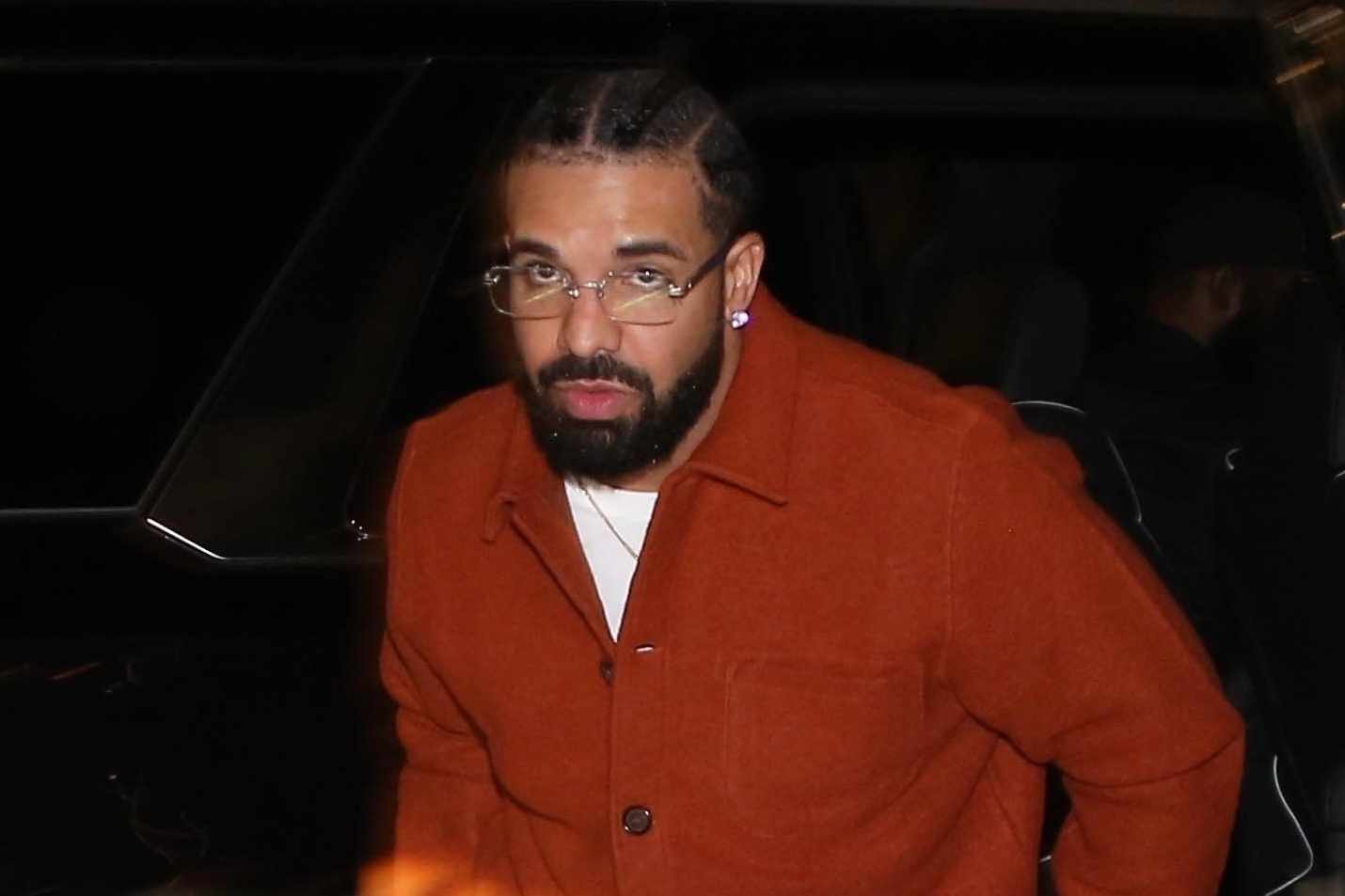 Drake wears a red shirt over white pants with thin-rimmed glasses on a night out in Los Angeles