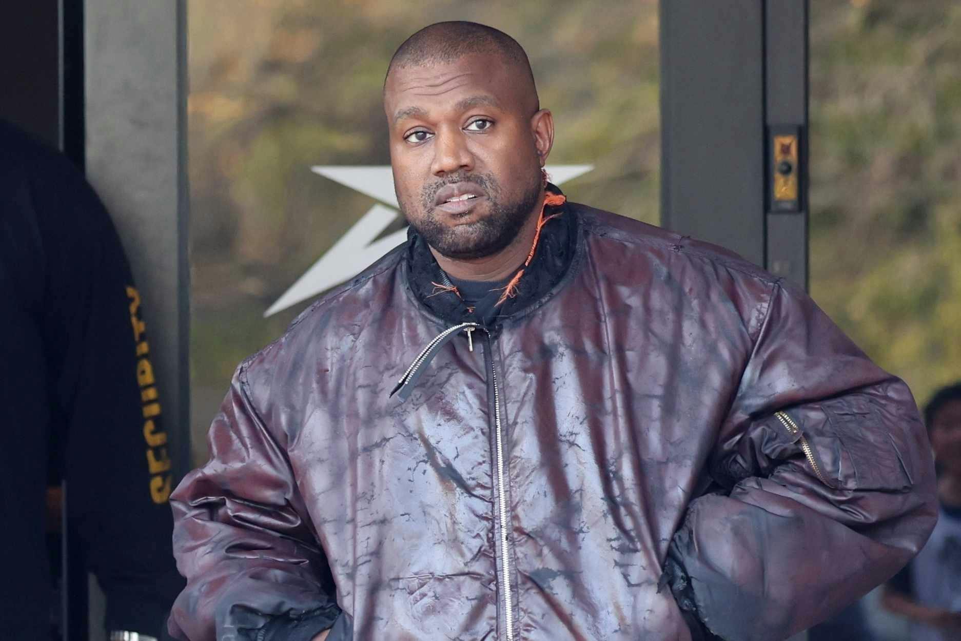 Kanye West is seen walking out of son Saint's basketball game wearing a bomber jacket, sweatpants, and socks