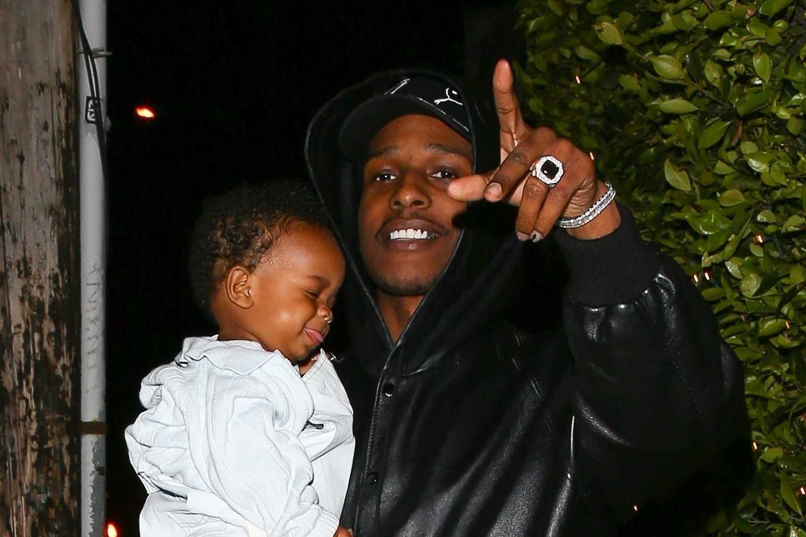 A$AP Rocky is seen wearing a black hoodie & PUMA hat holding his son RZA