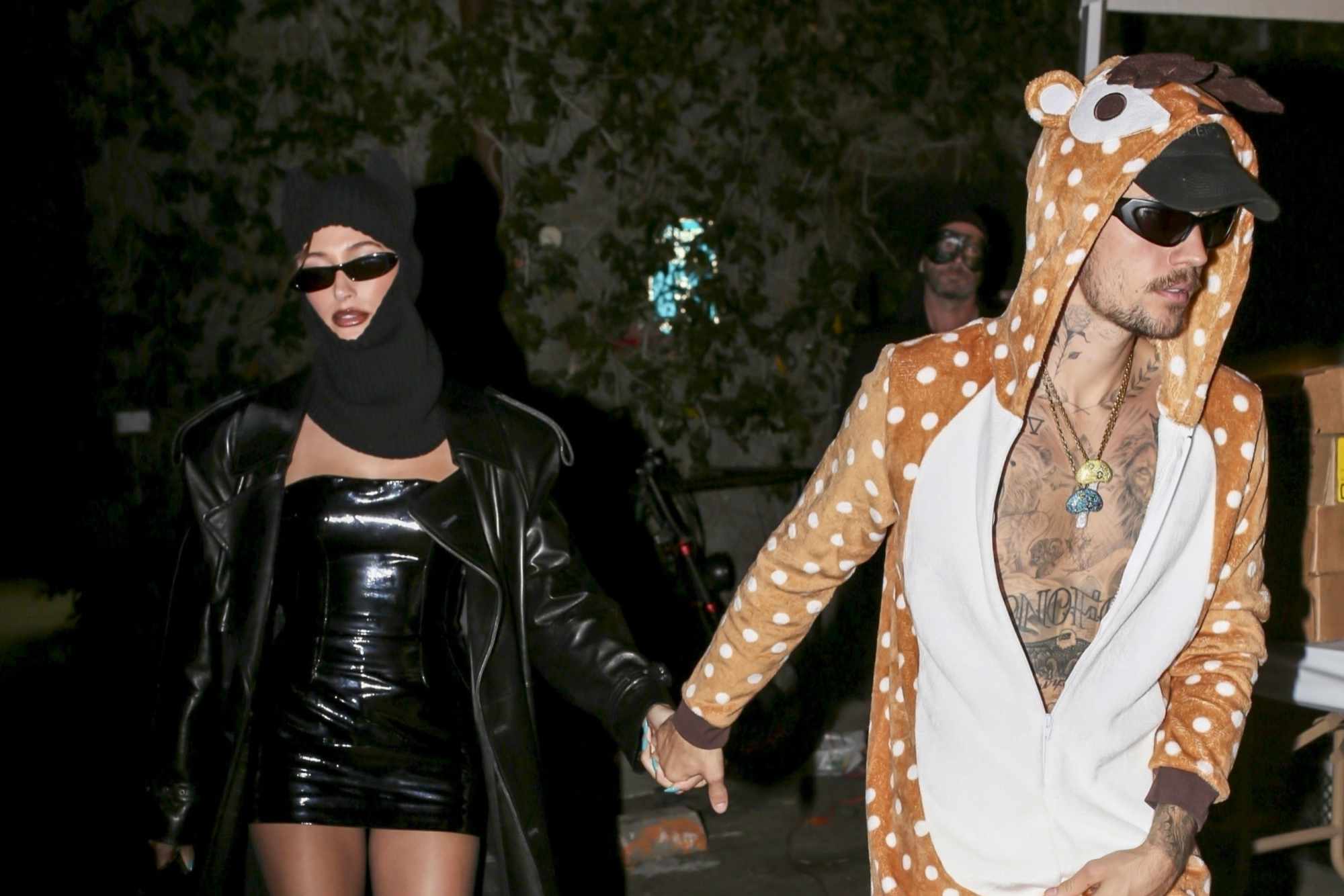 Justin & Hailey Bieber wear their 2023 Halloween costumes. Hailey is dressed in leather & Justin has a giraffe costume