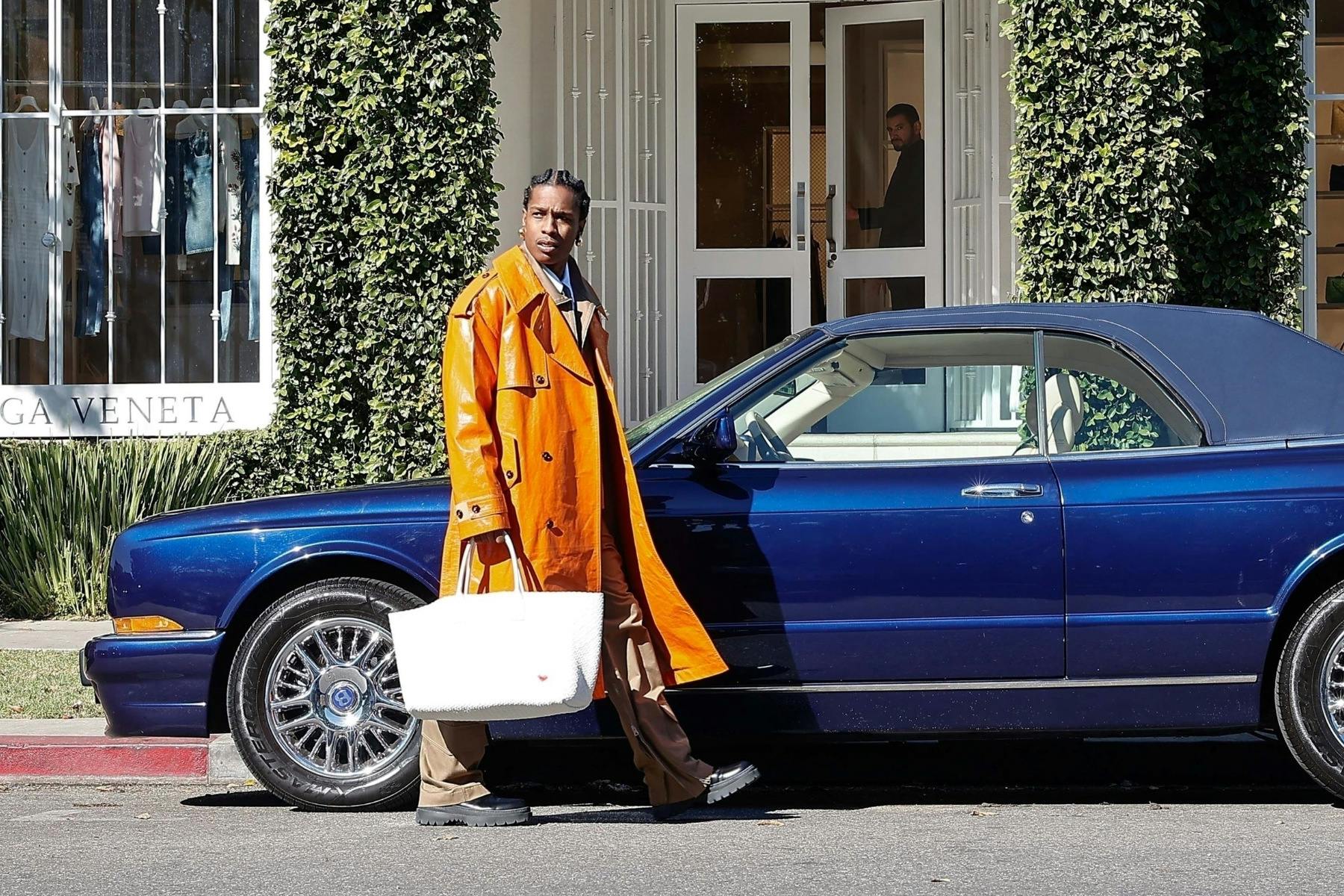 Asap Rocky wears black sunglasses, a leather jacket, Supreme sweatpants, and PUMA sneakers at the Bottega Veneta store in los Angeles