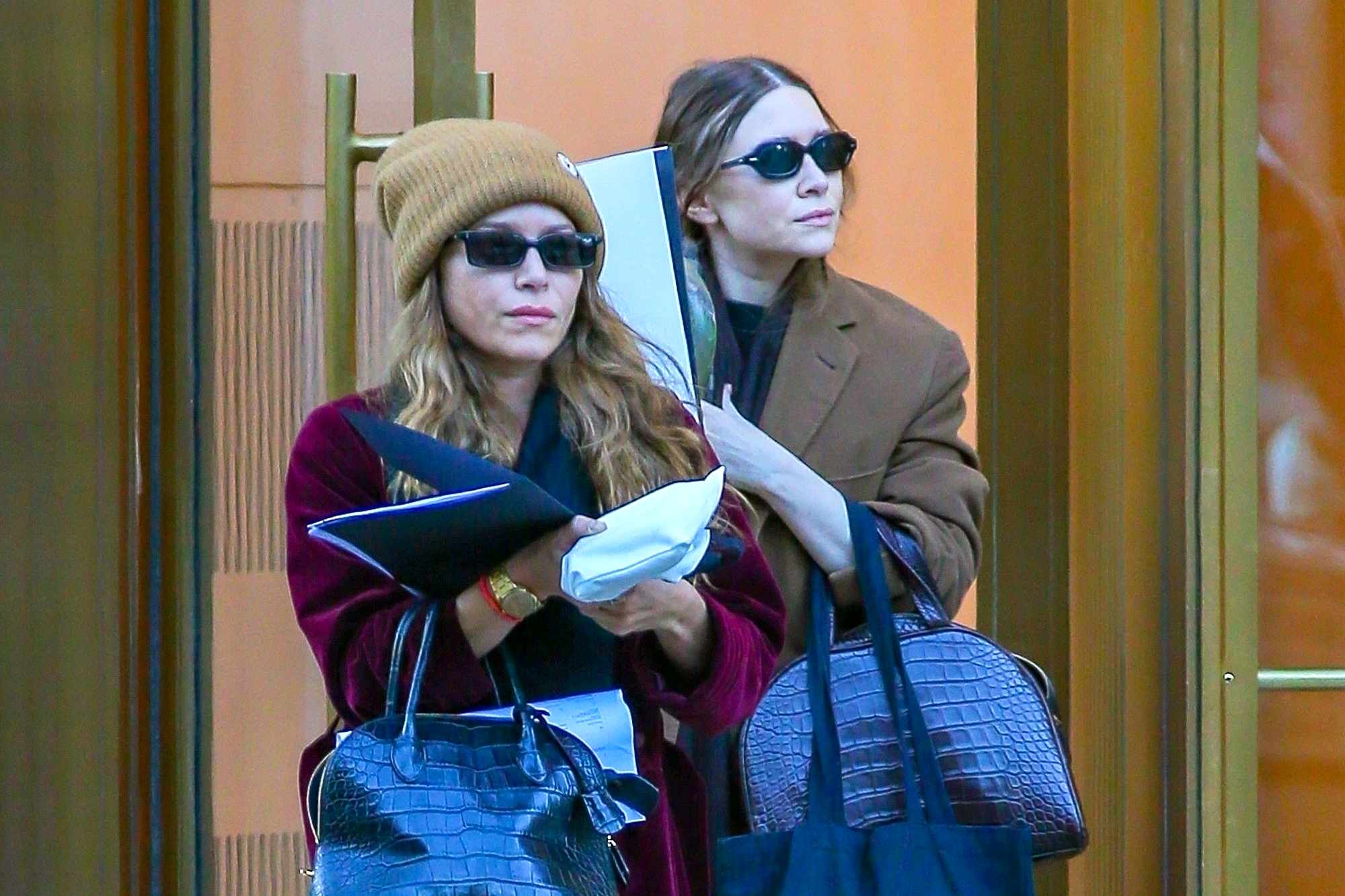 Mary-Kate & Ashley Olsen in New York on November 3 wear beanies, velvet coats, relaxed jeans, dark sunglasses & crocodile leather bags