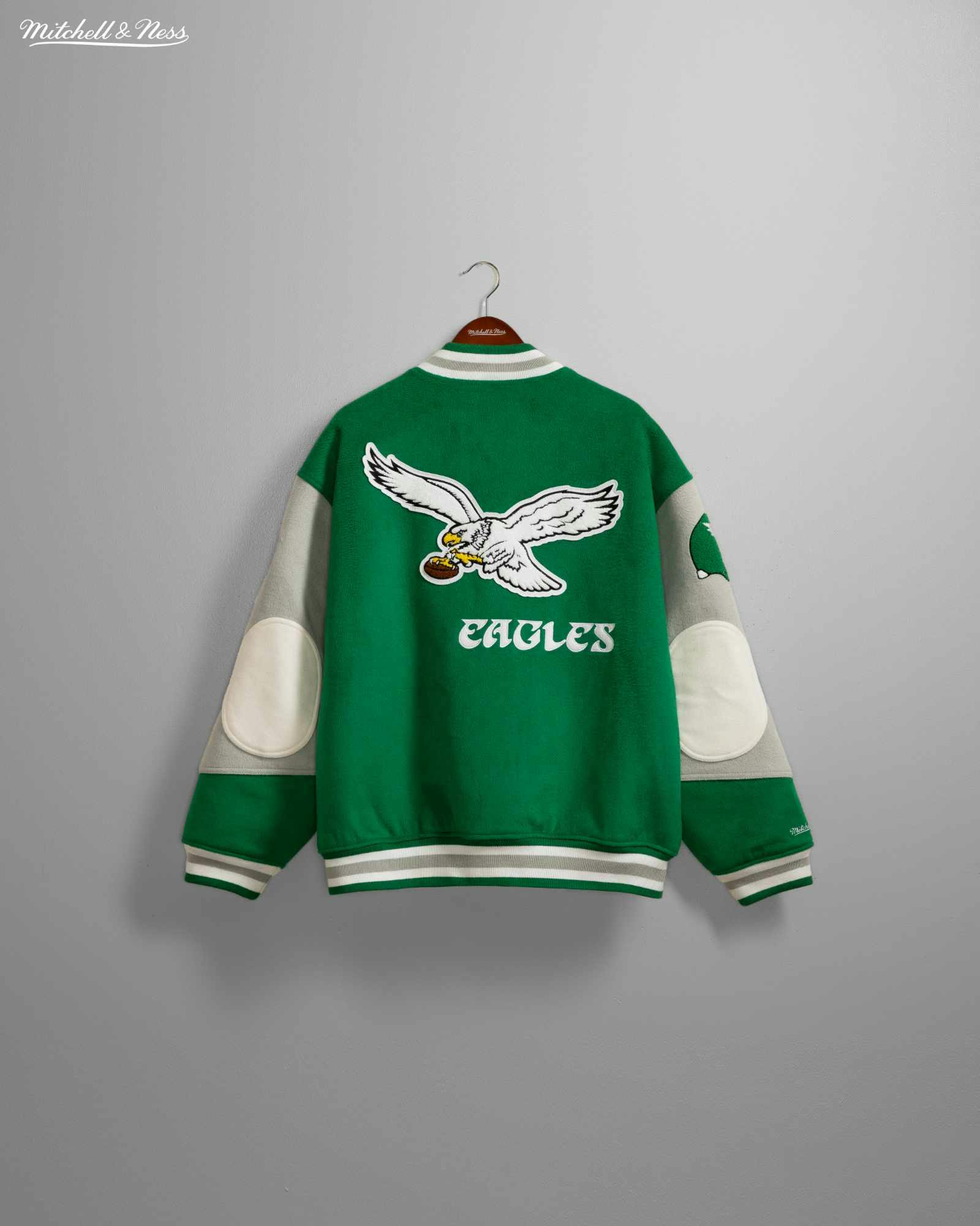 Product photos of Mitchel & Ness' Princess Diana Eagles jacket recreation in green wool and silver leather releasing in November 2023