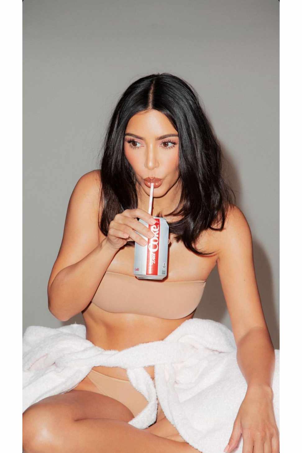 Kim Kardashian drinks a Diet Coke while wearing beige shapewear in a KKW Beauty campaign