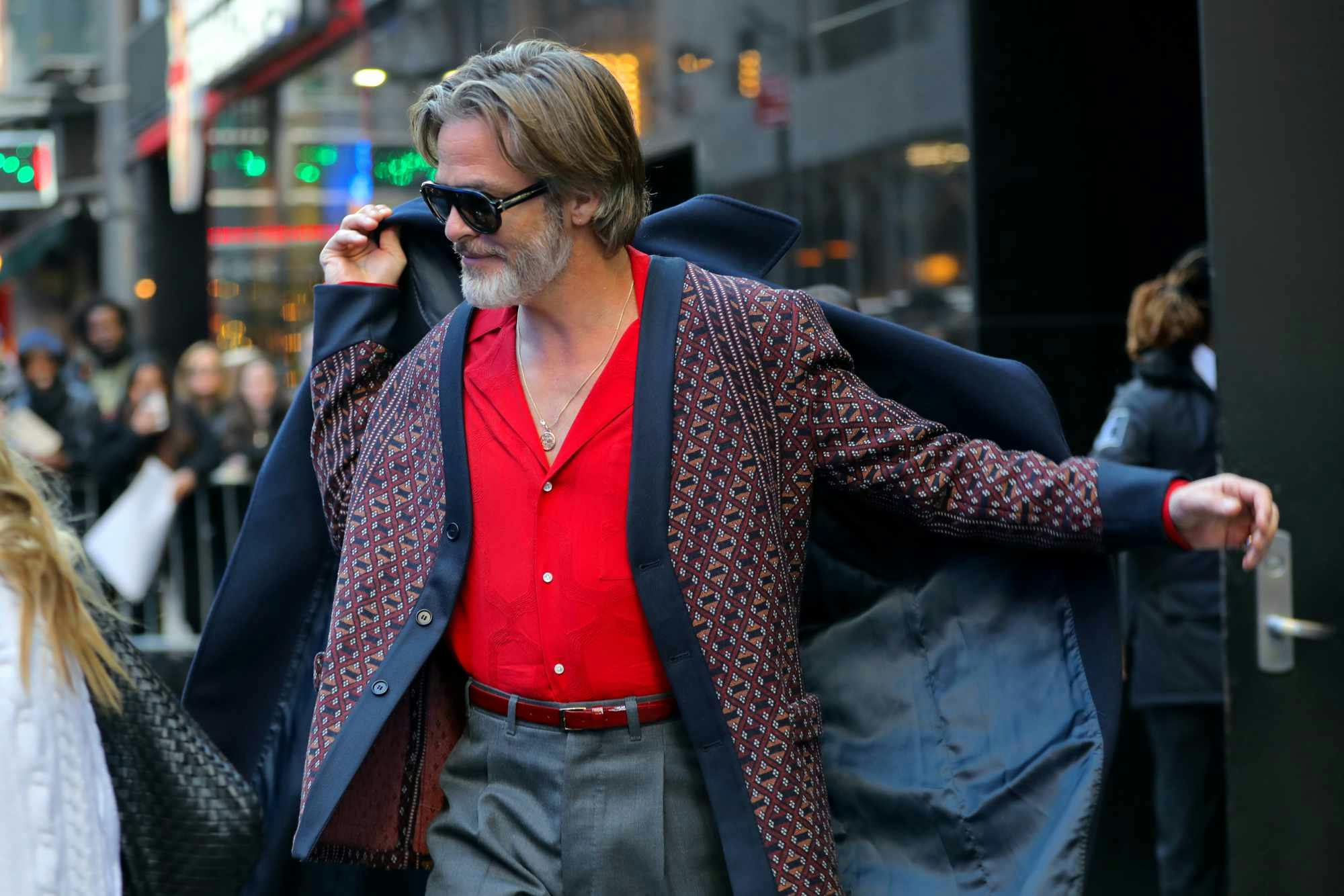 Chris Pine seen wearing a navy coat, grey cardigan, red shirt, and grey slacks outside of the Today show