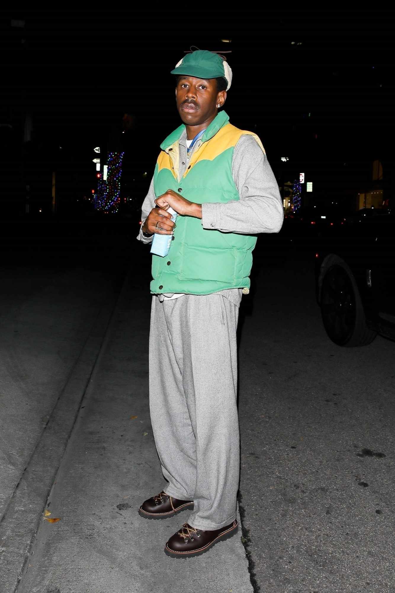 Tyler the Creator wears a green hat, puffy vest, grey hoodie and sweatpants with hiking boots at a WME red carpet event in Los Angeles in November 2023