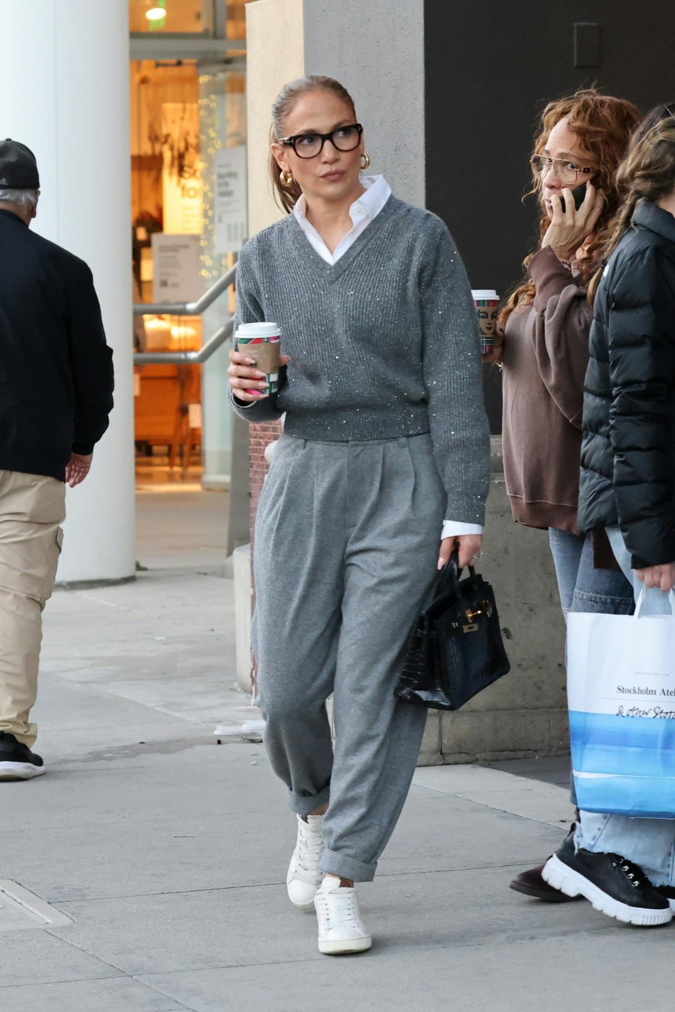 JLo wears a grey sweater, pleated pants, white shirt & Hermes Birkin bag