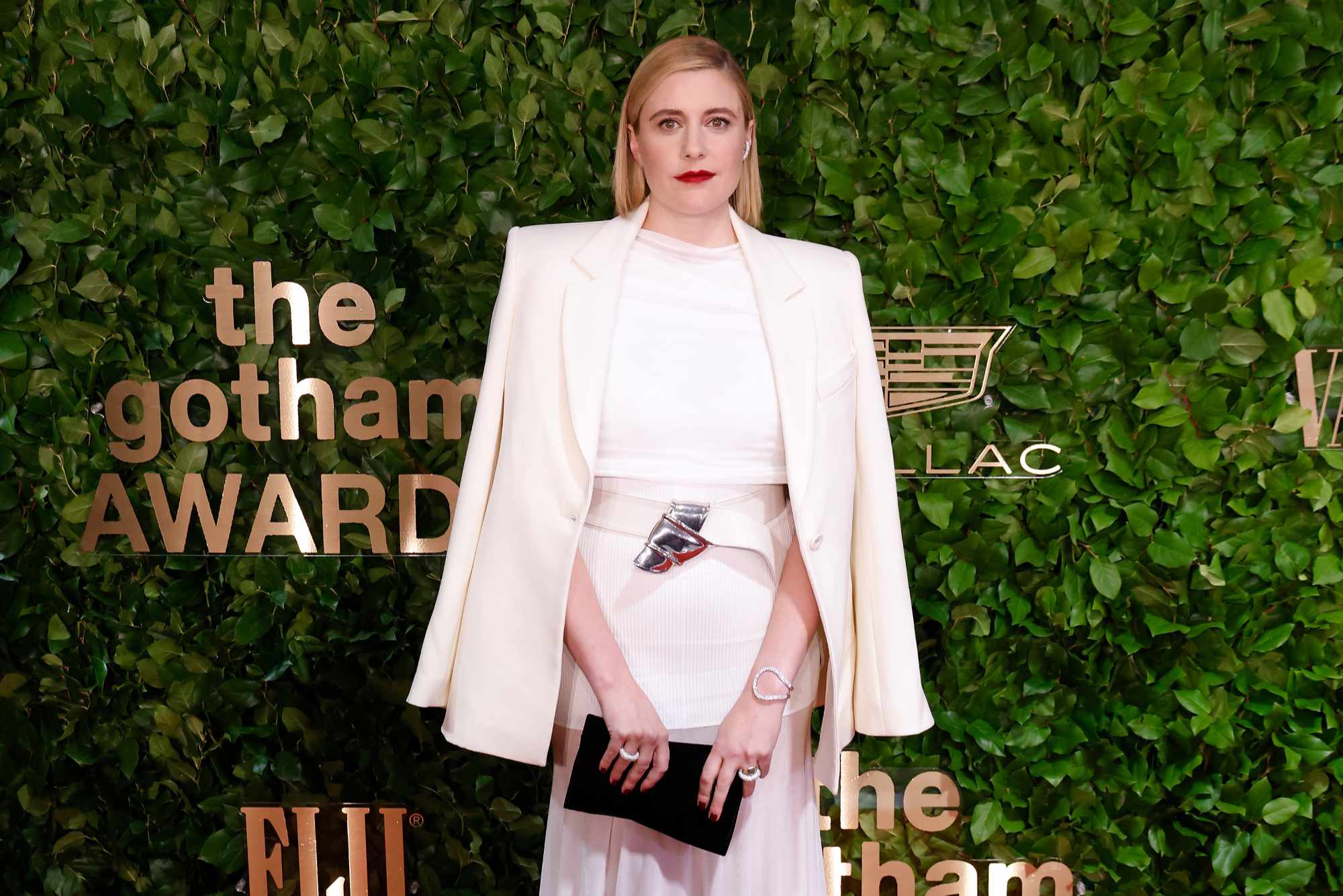 Greta Gerwig's red carpet look at the 2023 Gotham Fashion Awards, including a white blazer, white shirt, silver belt, and white skirt