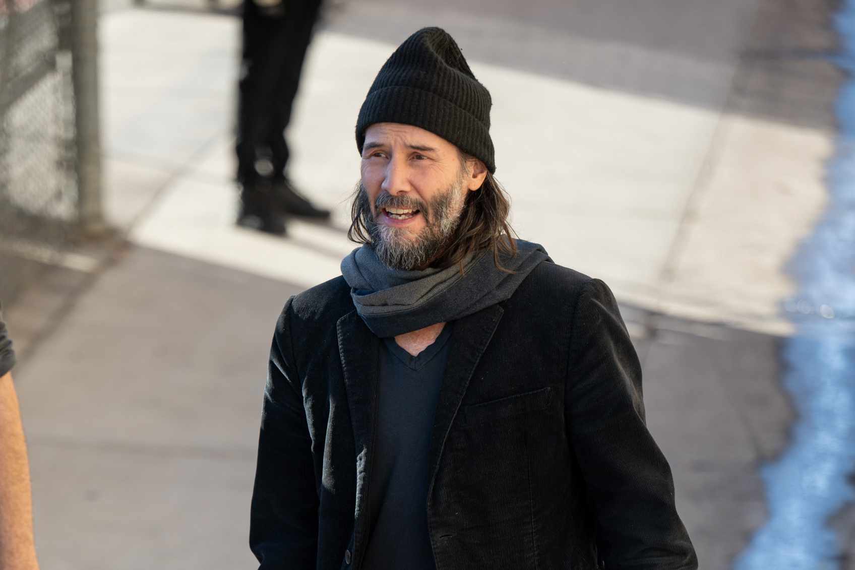 Keanu Reeves wears a beanie, brown blazer, sweater, jeans, and beige boots to perform on Kimmel with his band, Dogstar